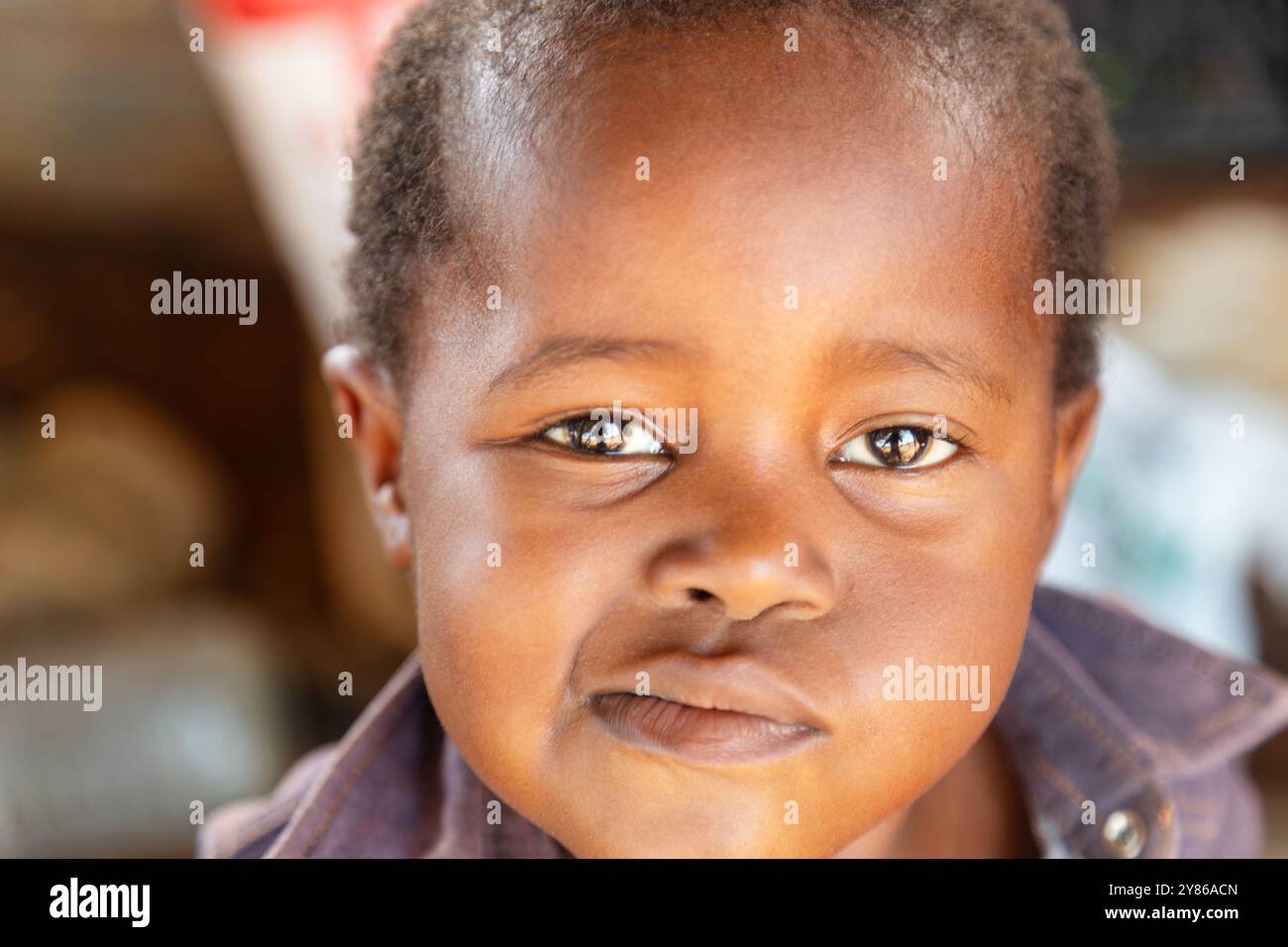 afrikanisches Kinderporträt des Dorfes mit ausdrucksstarkem Gesicht, das Gesichter in den Mund zieht Stockfoto