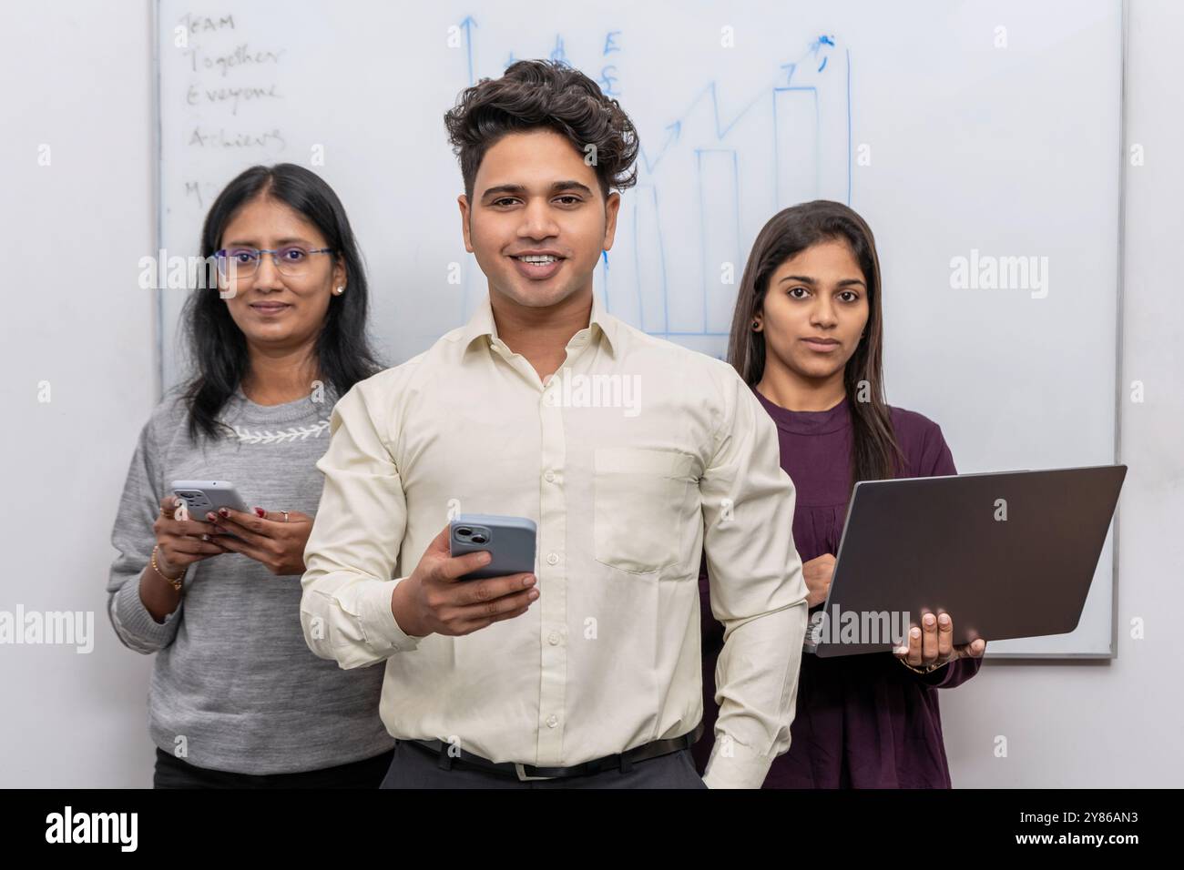 Das dreiköpfige Team von Admin Operations verfügt über einen selbstbewussten Teammanager, der an vorderster Front steht und zwei unterstützende weibliche Mitarbeiterinnen unterstützt Stockfoto