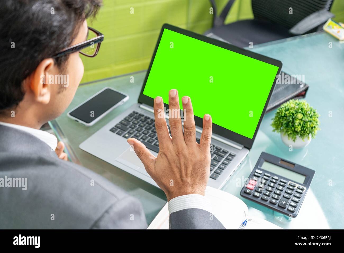 Ein fröhlicher Geschäftsmann wird in einem modernen Büro gesehen, der sich in einem produktiven Online-Gespräch mit einem Kunden im Ausland befindet. Sein positives Verhalten spiegelt sich wider Stockfoto