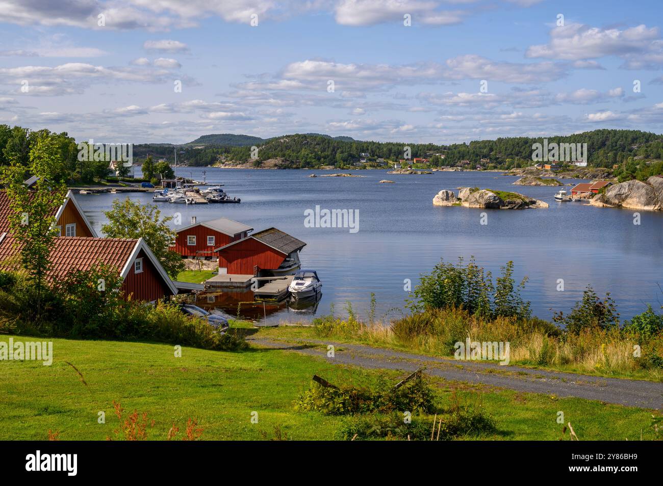 Inseln in der Sonne: Typische Waldlandschaft mit Spiegeln und idyllischen Sommerhäusern von der Insel Skåtøy aus gesehen. Kragerø Archipel, Telemark, Norwegen. Stockfoto