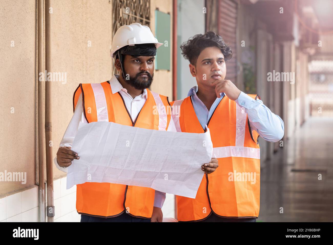 Ein Bauingenieur und ein Elektroingenieur konzentrieren sich auf die Prüfung von Baudetails, Projektaktualisierungen auf einer gewerblichen Industriebaustelle, Stockfoto