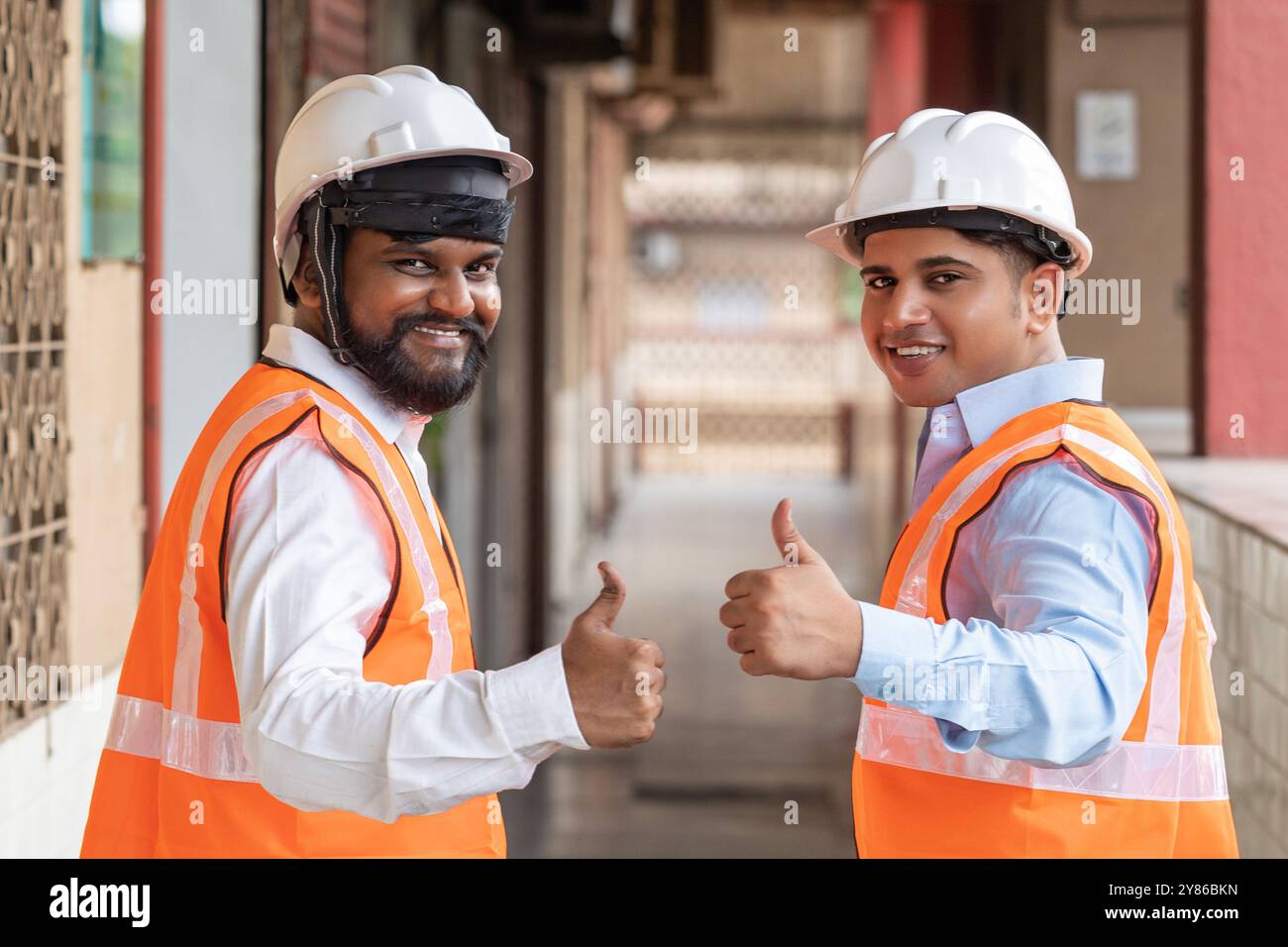 Zwei zufriedene Bauarbeiter geben auf der Baustelle den Daumen hoch und symbolisieren Zufriedenheit, Zuverlässigkeit und Vertrauen in die Zufriedenheit der Mitarbeiter. Stockfoto