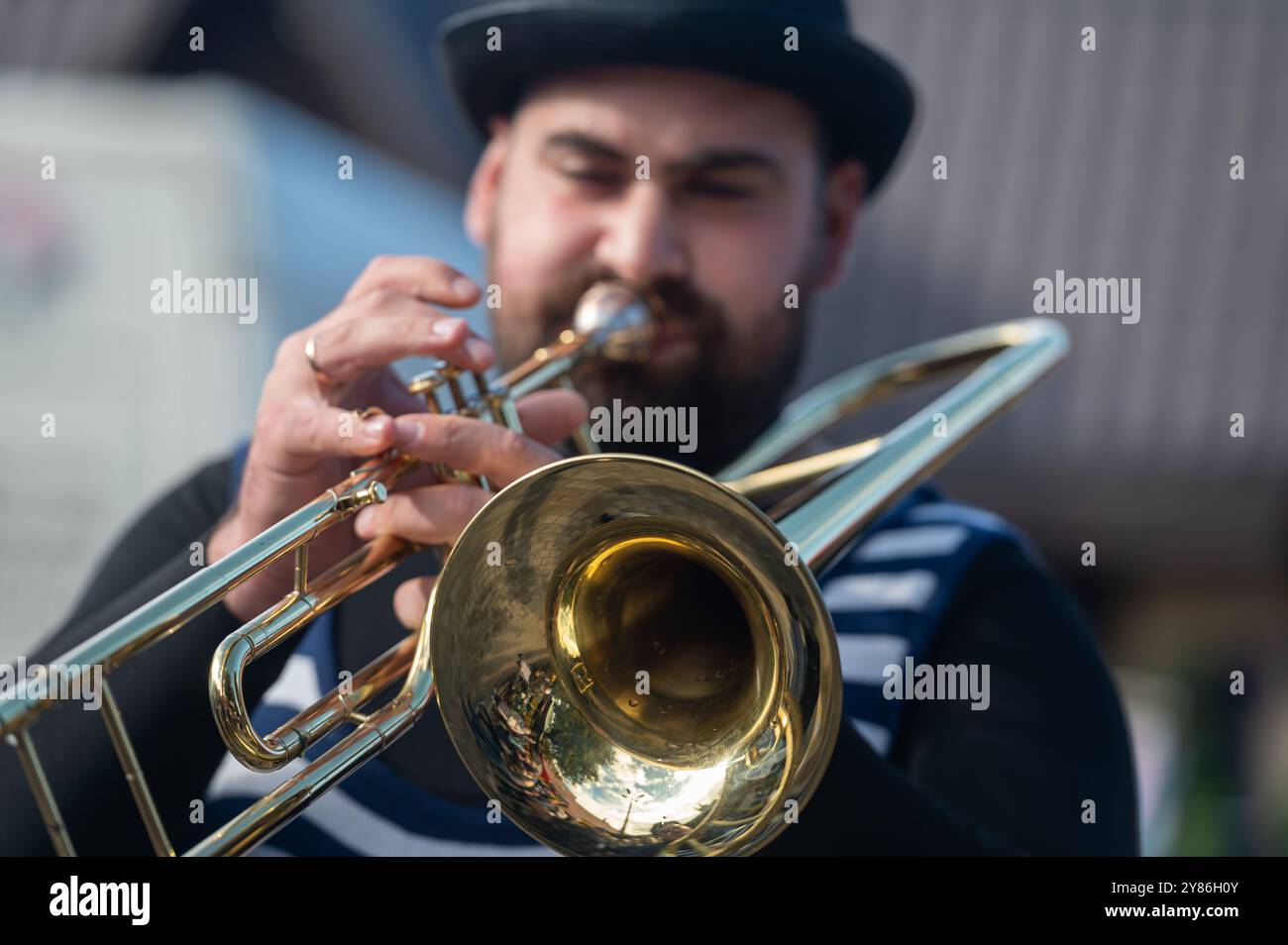 Tukums, Lettland - 28. August 2024: Männlicher Musiker spielt bei einer lebhaften Aufführung im Freien eine glänzende Blechtrompete Stockfoto