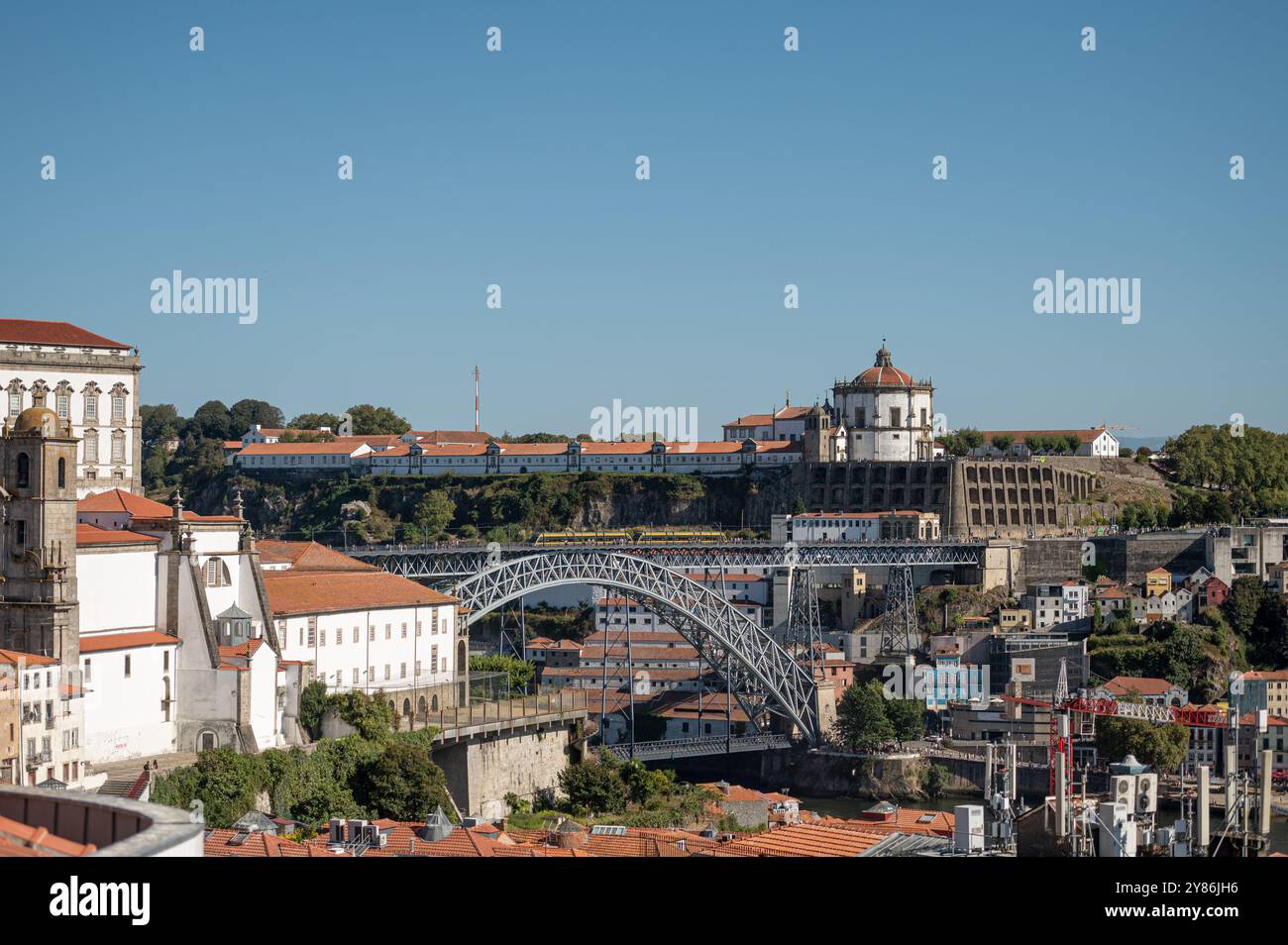 Porto, Portugal - 13. September 2024 : farbenfrohe Gebäude und ein Zug, der an einem sonnigen Tag die berühmte Brücke in Porto überquert Stockfoto