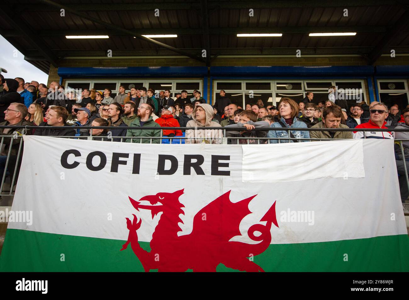 Die Zuschauer in der Haupttribüne sehen die Action in der zweiten Halbzeit, während Caernarfon Town (in Gelb) Crusaders in einem ersten Qualifikationsrunde der Europa Conference spielt Stockfoto