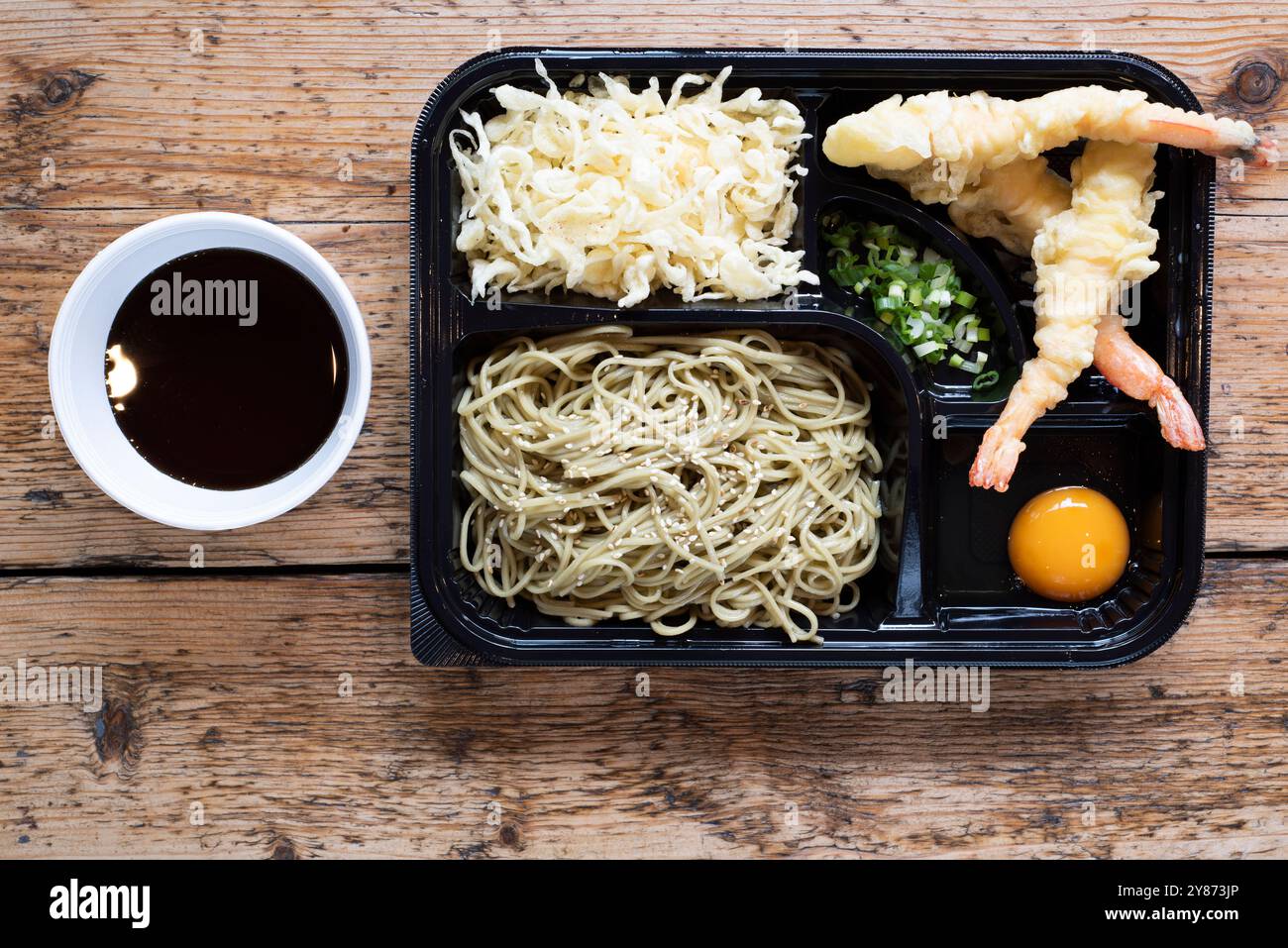 Chinesische Tempura-belegte King Garnelen-bento-Box, serviert mit Nudeln, eingelegtem Gemüse und einem rohen Eierdip Stockfoto