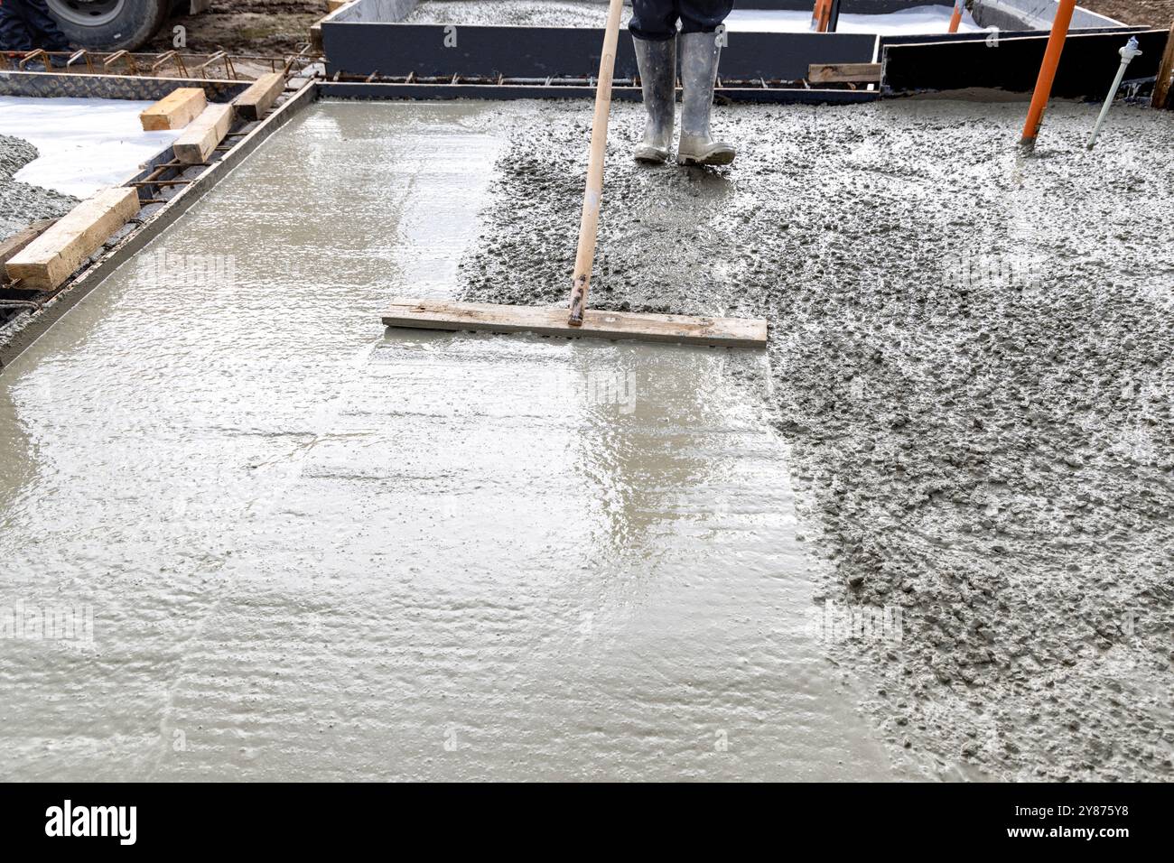 Arbeiter-Bauarbeiter, der Beton einer Platte auf einer Baustelle glättet Stockfoto
