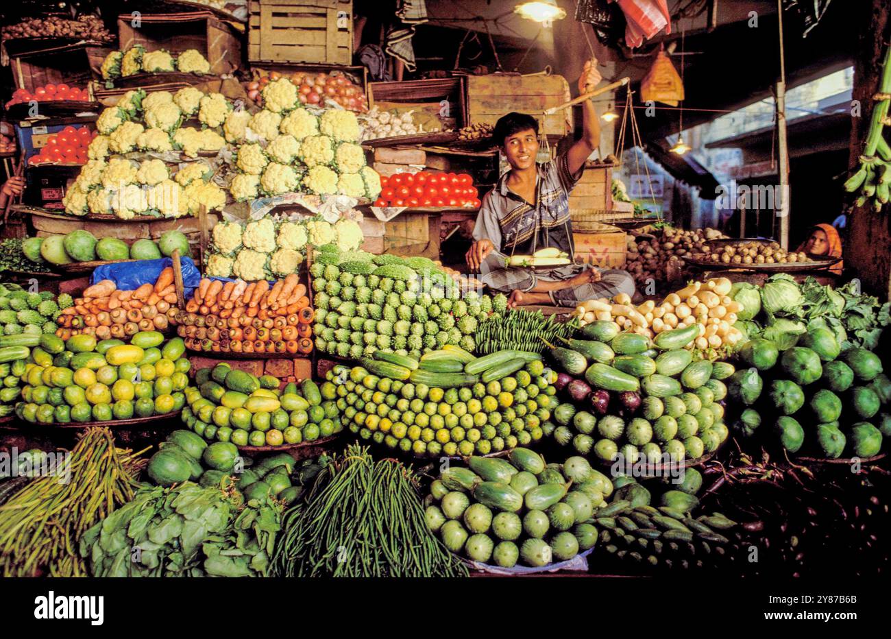 Bangladesch, Dhaka, Marktverkäufer mit Waage in einem Gemüsestand. Stockfoto