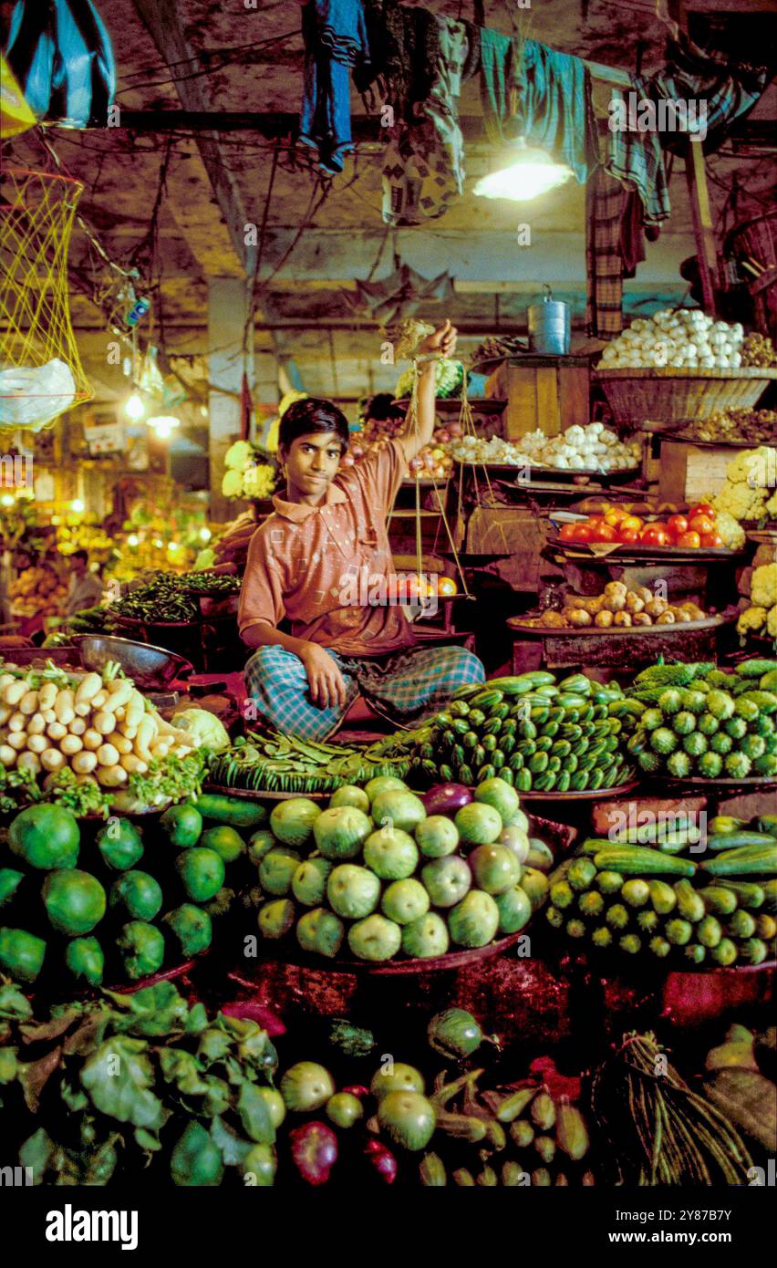 Bangladesch, Dhaka, Marktverkäufer mit Waage in einem Gemüsestand. Stockfoto
