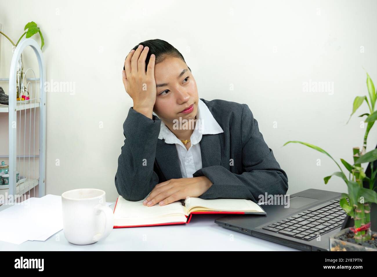 Young Business Manager weibliche Bürorezeptionistin mit Telefon und Notizblock gibt Gesten, die im Laptop-Kundenservice arbeiten und Papierkram erledigen Stockfoto