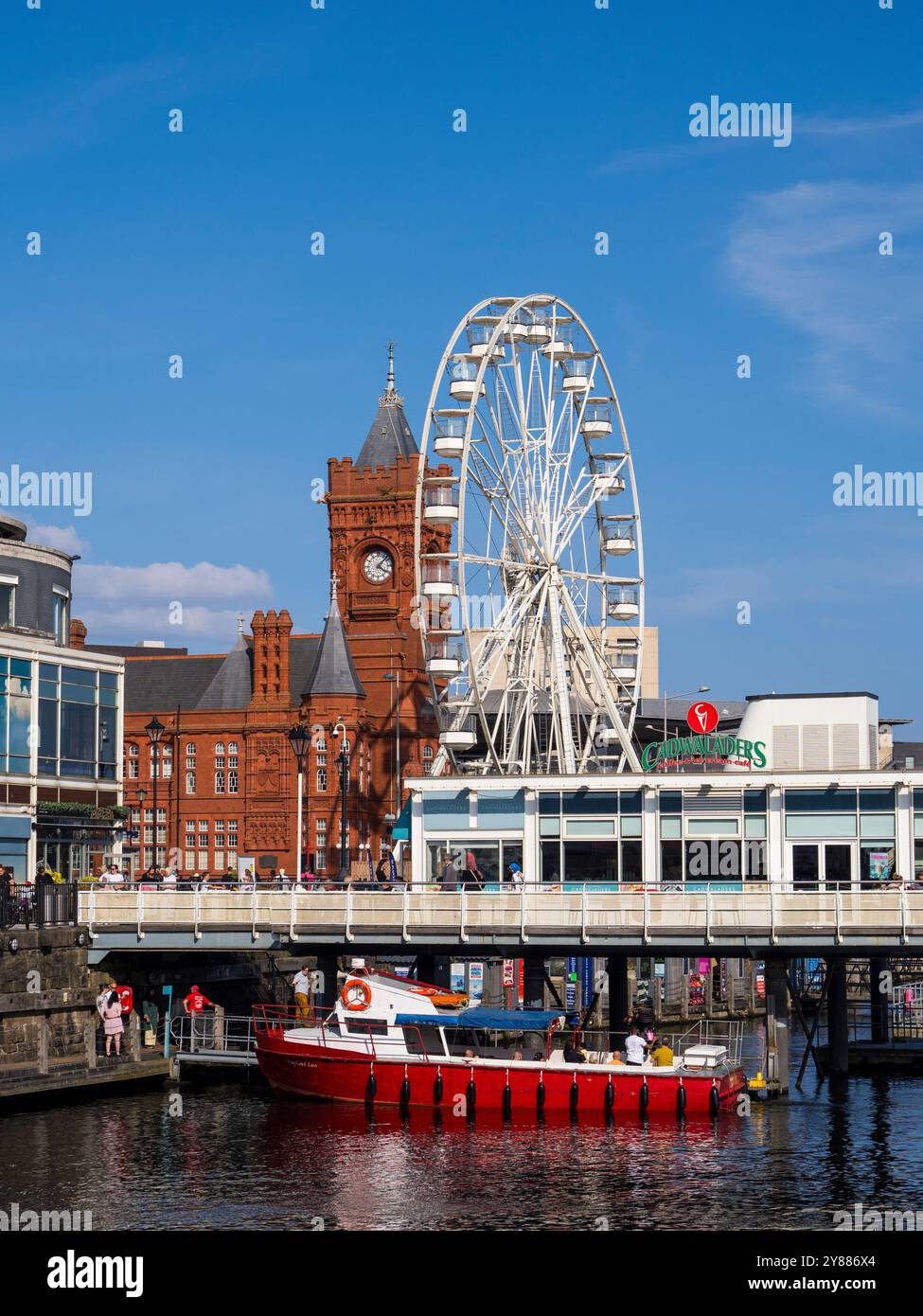 Red Tour Boat, die Waterfront in Cardiff Bay, mit Giant Wheel und Pierhead Building, Cardiff, Wales, Großbritannien, GB. Stockfoto