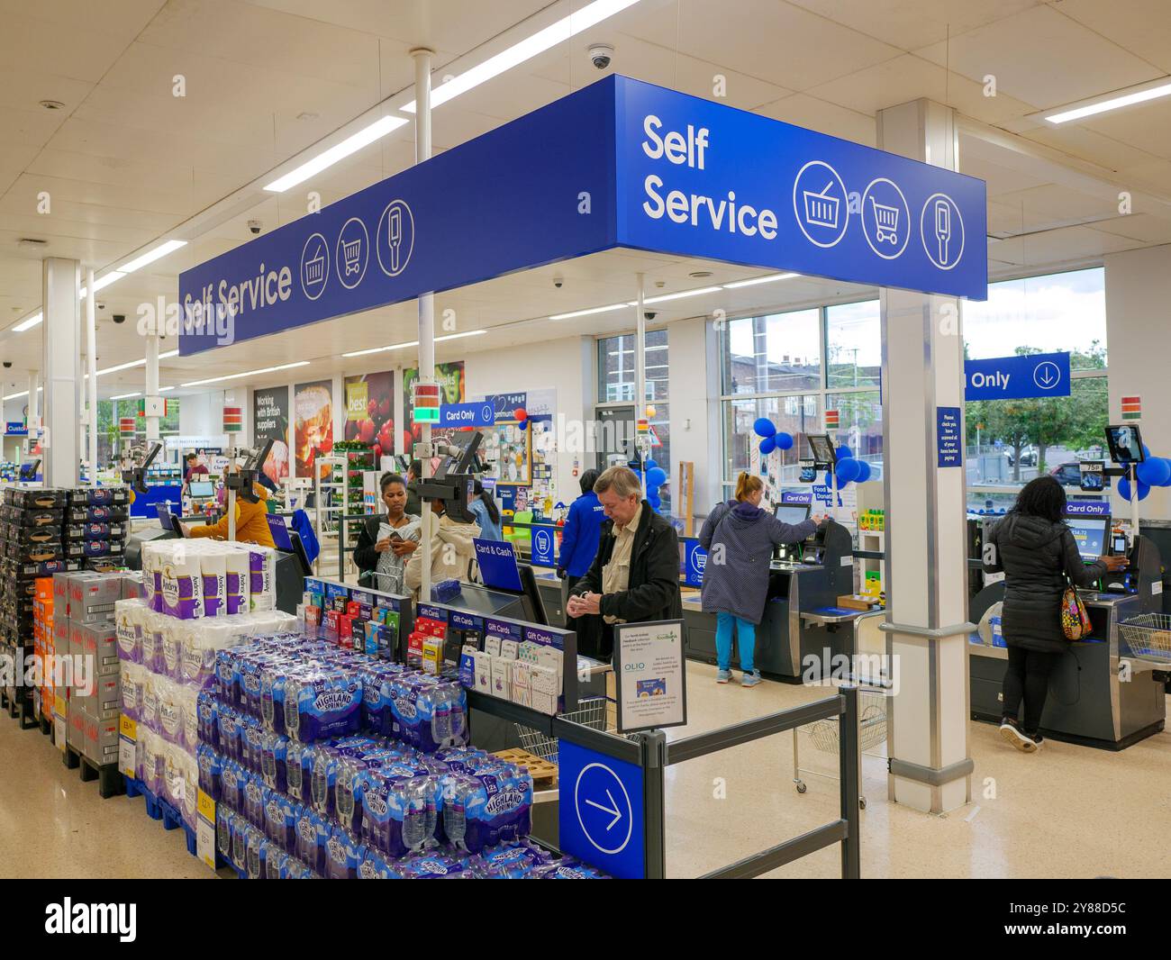 Leute, die für ihren Einkauf an den Selbstbedienungskassen in einem Tesco-Supermarkt, Großbritannien, bezahlen Stockfoto
