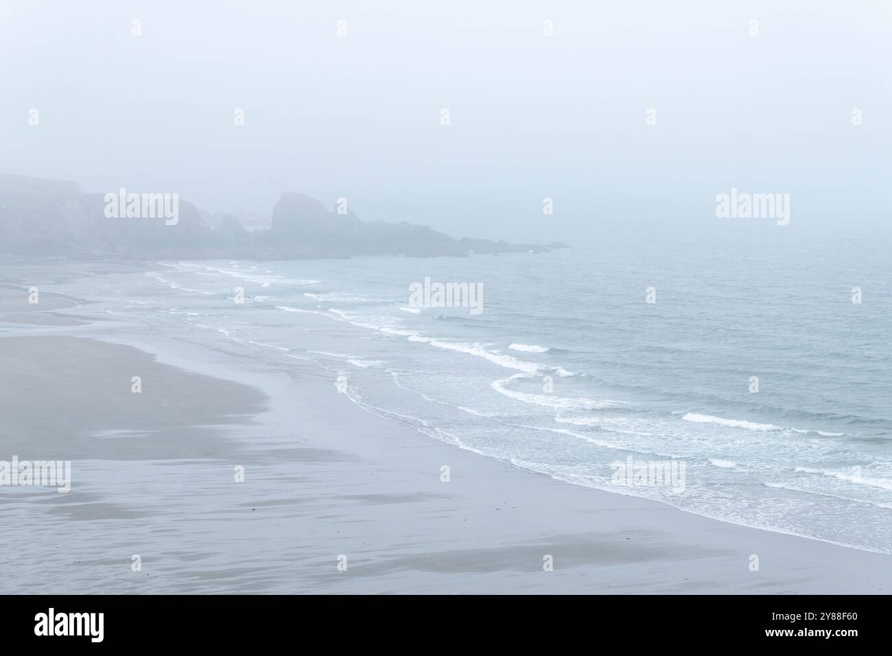 Bewölkter und nebliger Bunmahon Beach, Irland – sanfte Wellen und nebelige Küstenlandschaft Stockfoto