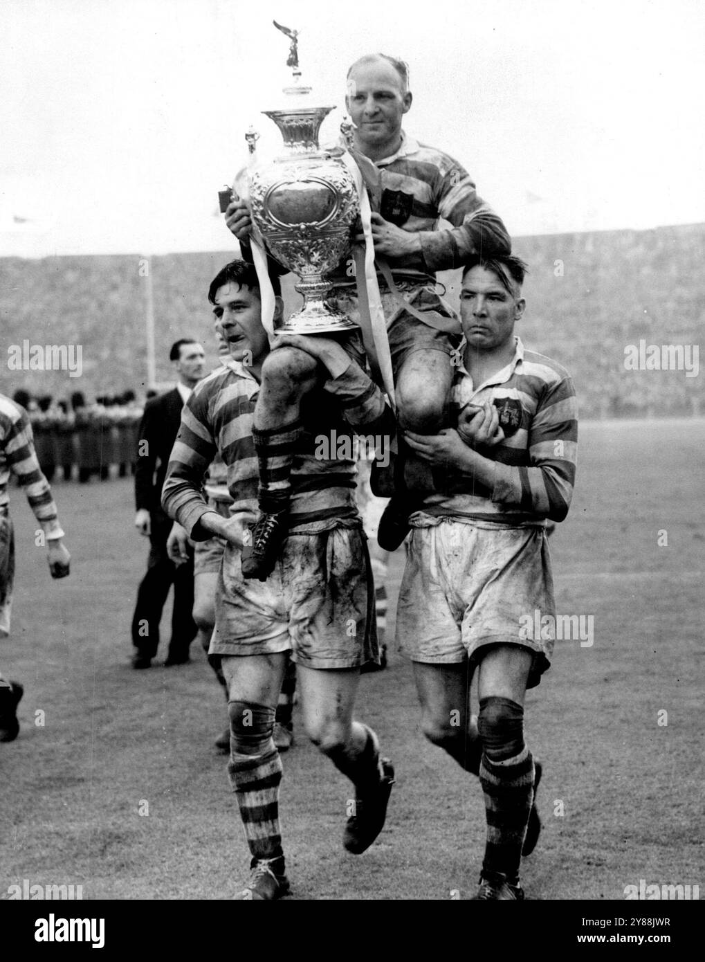 Wigan gewinnt den Rugby League Cup - Captain Mountford hat den Vorsitz -- C.R. Mountford, wird triumphierend von seinen Teamkollegen geleitet, während er heute (Samstag) den Rugby League Cup in Wembley, London, hält. Wigan hatte Sarrow, das andere Team im großen Finale, besiegt Zwei Reifen und zwei Tore zu gewinnen. Mai 1951. (Foto von Reuterphoto). Stockfoto