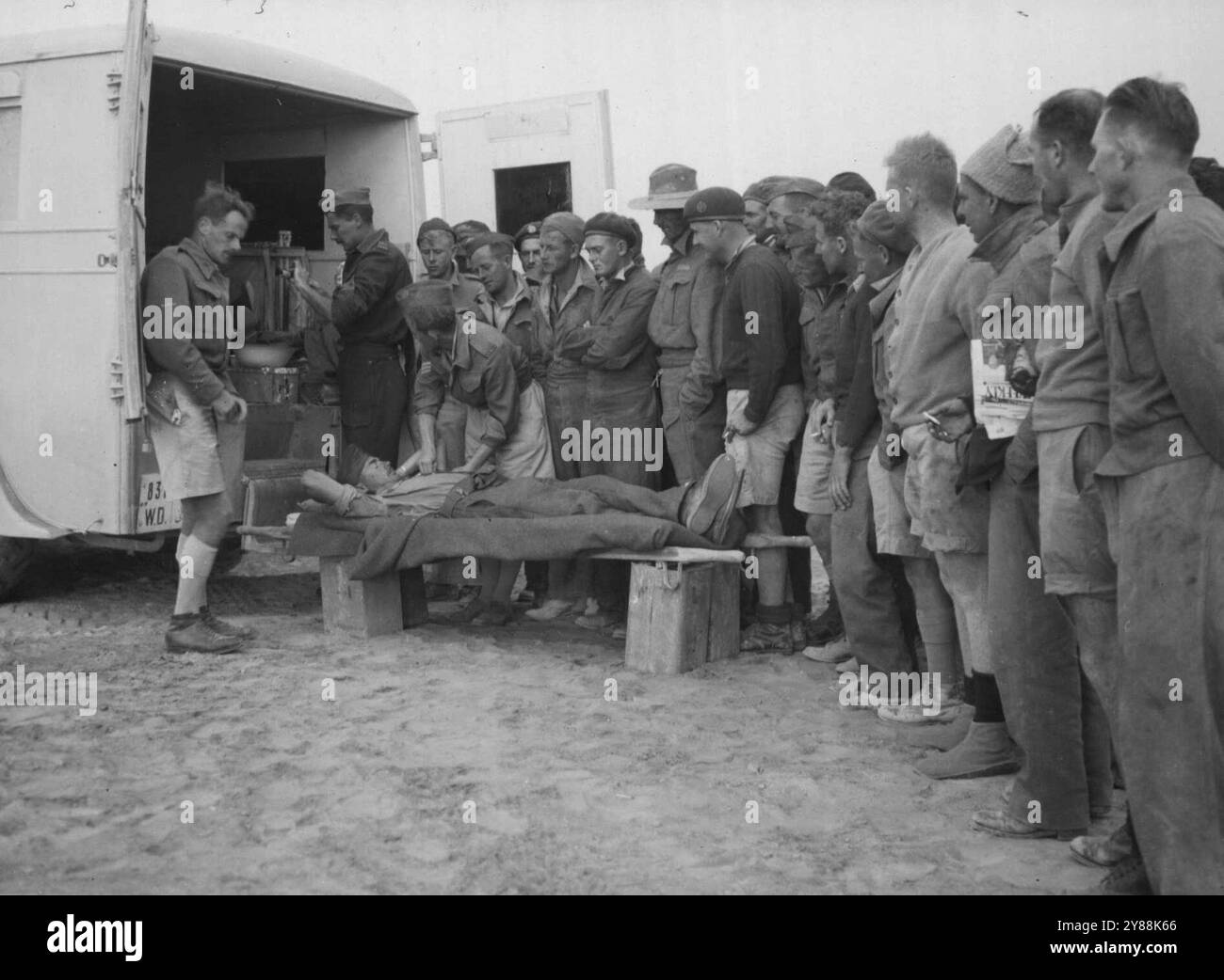 Die Antwort auf einen dringenden Ruf in der Wüste nach Blutspendern. Als die Opfer nach schweren Kämpfen in der libyschen Offensive in die Umkleidestationen zurückkehren, musste eine medizinische Einheit sofort mehr Blut für Transfusionszwecke benötigen. In der Nähe gab es eine Royal Australian Air Force Geschwader. Ein Anruf um ihre Hilfe wurde gemacht, und jeder Mann in der benötigten Blutgruppe meldete sich freiwillig als Spender. Dieses Bild zeigt die Aufstellung der Freiwilligen der Flieger. Die meisten von ihnen waren direkt von ihrer Arbeit an der Wartung von Kampfflugzeugen gekommen. Januar 1942. (Foto von A.I.F. Photography). Stockfoto