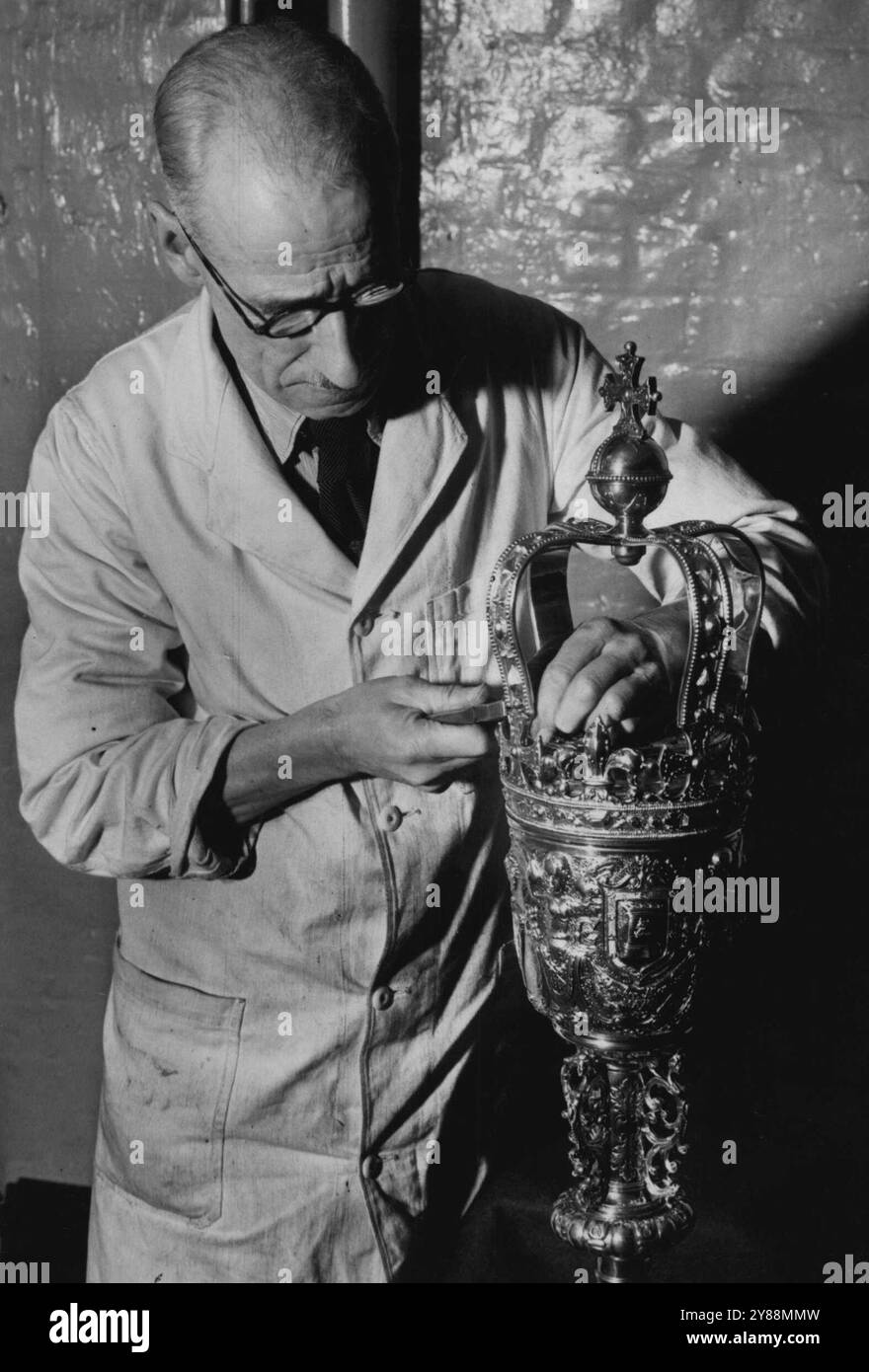 Craftsmen Repair Gravesends Historic Mace -- bei den London Works of Mapping und Webb arbeitet Mr. W. E. Jones an der Gravesend Mace. Gravesends historische Keule, 240 Jahre alt und einmal in Pfandstein gelegt, wird von den Handwerkern der bekannten Silberfirma Mapping and Webb, London, repariert. Die Keule, die zu den kunstvollsten des Landes gehört, ähnelt dem Großen Keule von Westminister sehr stark; sie ist aus Silber mit einer Oberfläche aus Gold. Der Kopf kann zur Verwendung als Tankwagen abgeschraubt werden. 1851 war die Corporation verschuldet und der Sheriff nahm die Keule anstelle von Bargeld. Erst 1881 war das corporatio Stockfoto