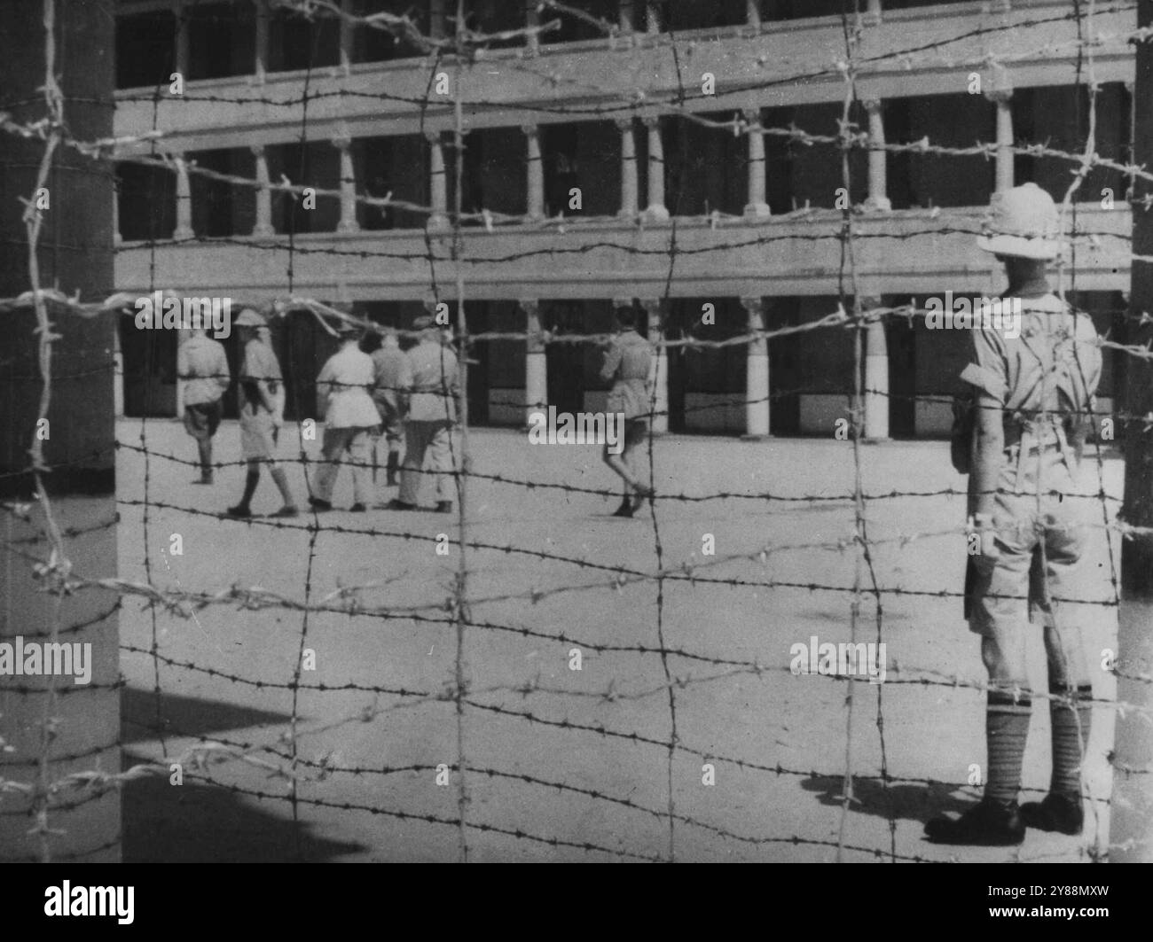 Erste italienische Kriegsgefangene -- durch den Stacheldraht passieren italienische Offiziere, einige der ersten Kriegsgefangenen im Nahen Osten, vor einem britischen Wachposten in Ägypten. September 1940. (Foto: London News Agency Ltd.) Stockfoto