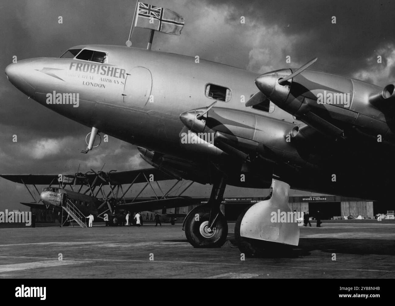 Sky-Liner von 1938 -- in Croydon, Londons Terminal-Flugplatz, fliegt Frobisher zum ersten Mal das britische zivile Flugzeugzeichen. Sie und vier Schwesterboote werden einige europäische Dienste von Imperial Airways betreiben. Sie fährt mit 212 km/h (341 km/h) Mit 22 Passagieren und E-Mails an Bord. Ihre Reichweite beträgt 1,770 km (1100 Meilen). Im Hintergrund steht der Veteran "Herakles" , der mehr Stunden geflogen und mehr Passagiere befördert hat als jedes andere Flugzeug der Welt. Ein neuer Standard für britische zivile Flugzeuge. Die Frobisher, Großbritanniens Linienschiff für die europäischen Dienste, fliegt die zivile Luft en Stockfoto