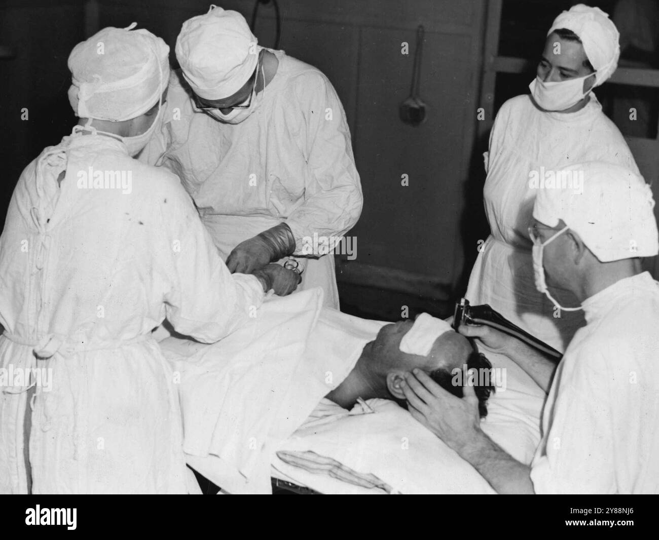 Eine Blinddarmoperation im Gange an einem australischen General Hospital in Lae. Der Chirurg ist ein Arzt in Sydney und der Anästhesist ein Arzt aus Westaustralien. Sie werden unterstützt von Schwester H. Benoit aus Melbourne vor der Kamera und von Schwester H. Wilson aus Melbourne zurück an die Kamera. September 1944. Stockfoto