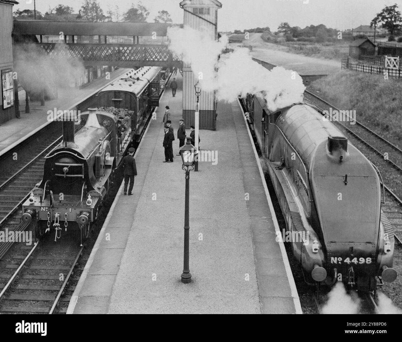 Das alte und das neue einzigartige Meeting auf dem L.N.E.R. Track in Stevenage -- der moderne 'Flying Scotsman' Express, der heute Nachmittag neben dem alten Zug an der Stevenage Station auftaucht. Anlässlich des Jubiläums des Bahnrennens nach Edinburgh im Jahr 1888, tauchte heute ein Zug mit Motor aus dem York Museum und einem historischen Rollhaken aus dem Bahnhof King's Cross in London, N. Die Passagiere des Flying Scotsman fuhren bis Stevenage, Hertford, wo sie auf den modernen Express gebracht wurden, um ihre Reise fortzusetzen. 30. Juni 1938. (Foto von Topical Press). Stockfoto