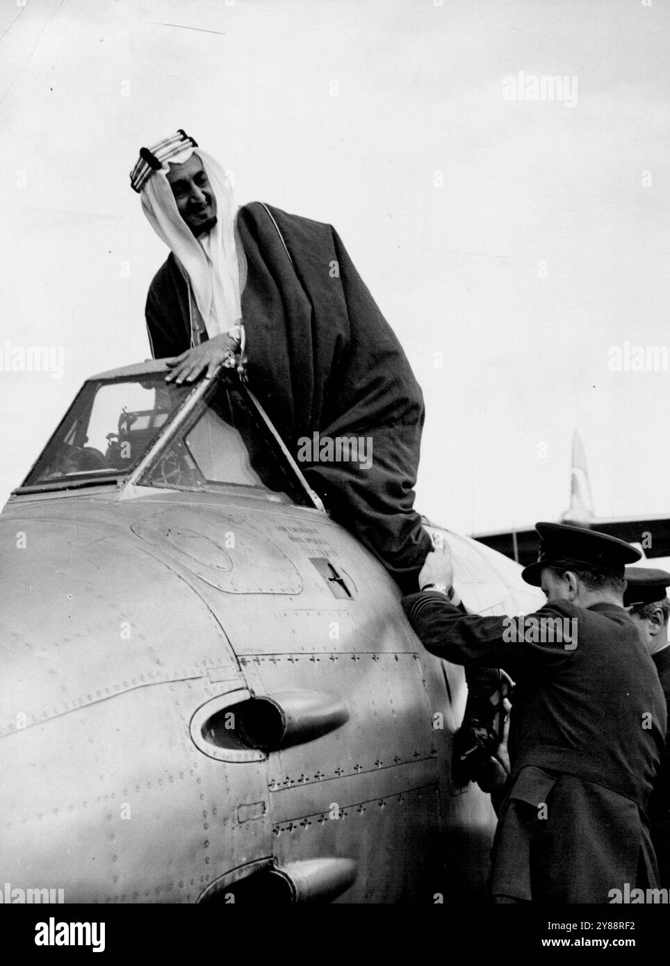 Emir in Jet Fighter -- der Emir Feisal fotografiert, als er in einen Golster Meteor Jet Fighter klettert, unterstützt von Wing Commander Donaldson (Einem Bruder des berühmten Geschwindigkeitsrekordhalters). Emir Feisal, Vize-Roy von Hedjaz und Außenminister Saudi-Arabiens, besuchte heute die Flugschau der R.A.F. in Biggin Hill. August 1951. (Foto: Paul Popper). Stockfoto