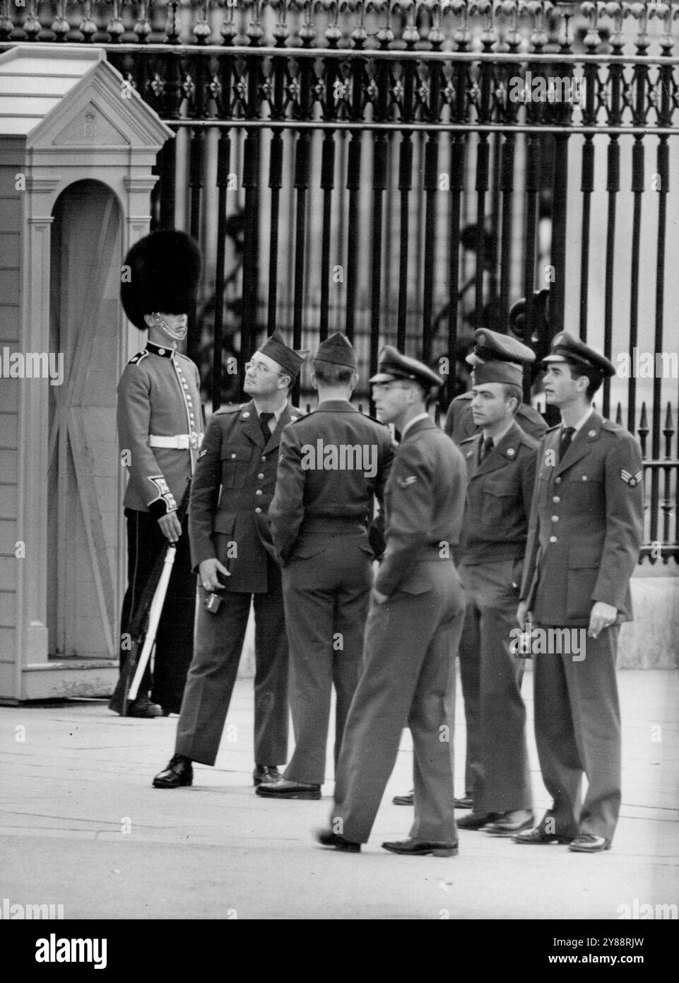 Was hat er, was wir nicht haben -- es ist ein angenehmer Sonntagnachmittag in der Mall. Ein schöner Tag zum Sightseeing, solange Sie nicht der Wachposten sind, der zurückblickt. Eine überfüllte Stunde brachte die Welt in einer Prozession vorbei an seiner Box, einschließlich einer interessierten Gruppe von Amerikanern, auf Urlaub in einer scharlachroten Tunika und Bärenfell. Man kann wetten, dass sie sagten: "Mann, ist er nicht etwas und sei genauso sicher, dass er nie einen Muskel mit einer Augenbraue bewegt hat. August 1954. (Foto: Paul Popper, Paul Popper Ltd.) Stockfoto