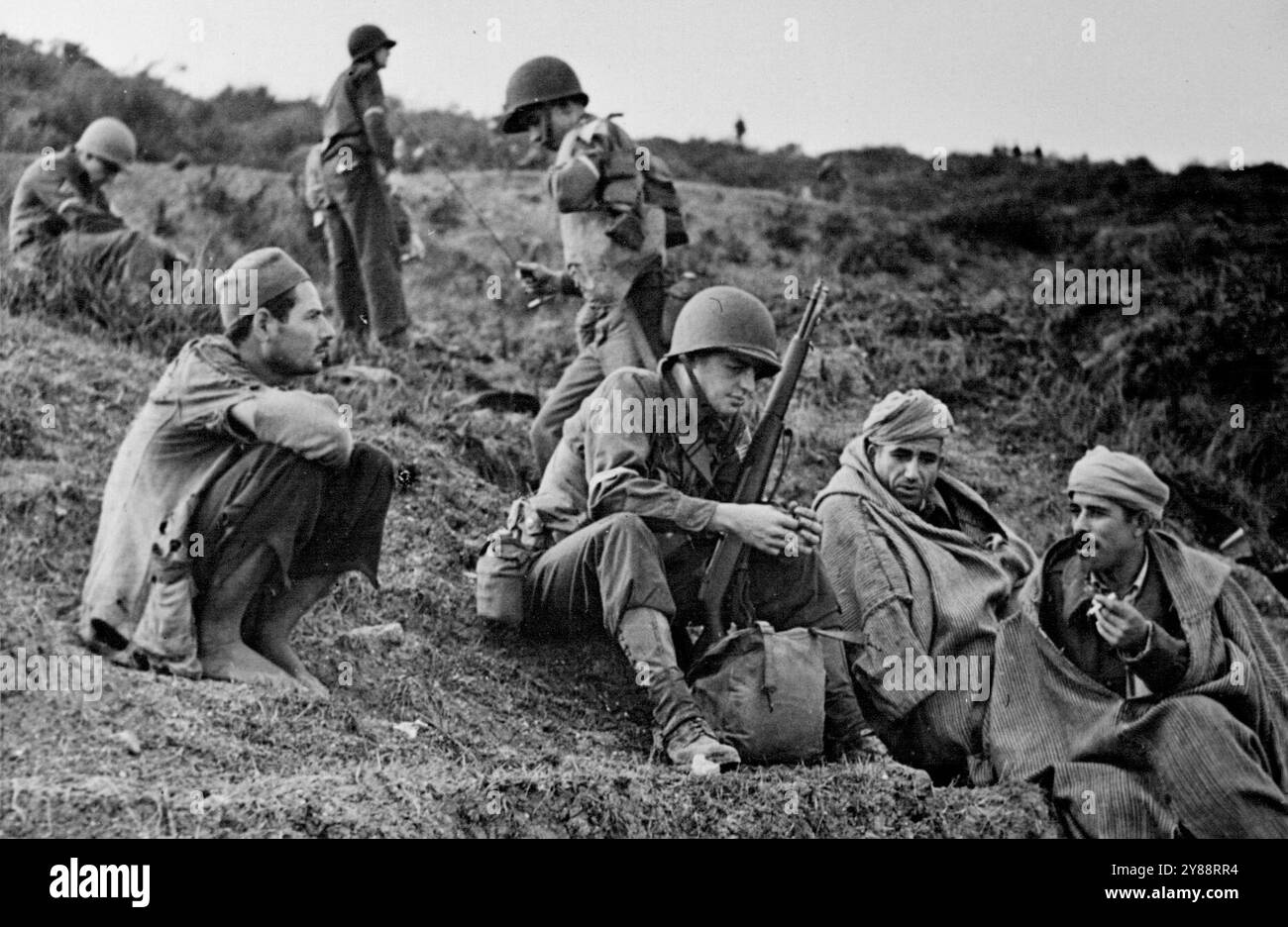 Ein amerikanischer Soldat, der mit drei Arabern spricht, während er auf den Weg wartet. Januar 1943. (Foto vom Department of Information, Commonwealth of Australia) Stockfoto