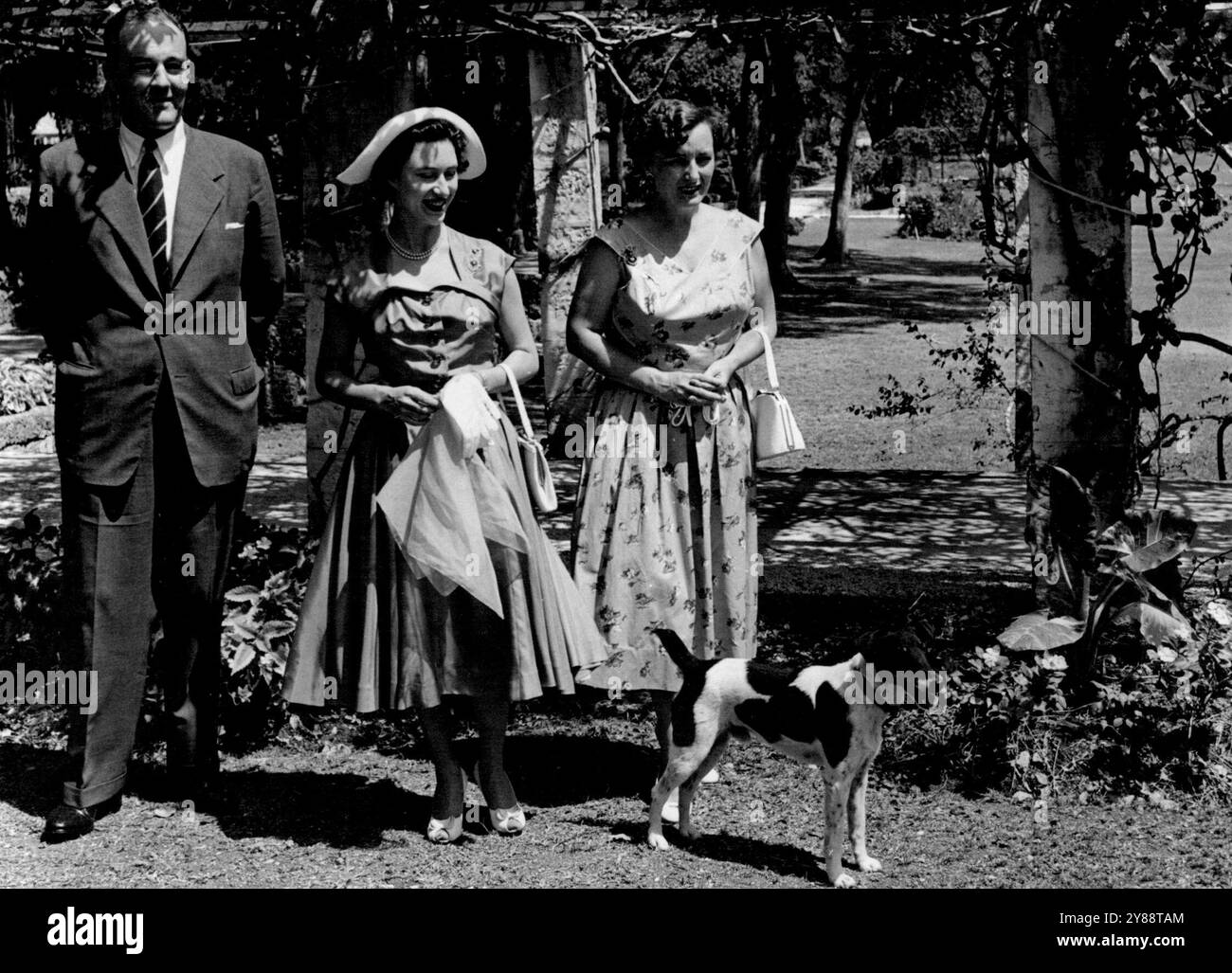 Prinzessin Margaret lächelt den kleinen Hund an, der darauf bestand, auf dem Foto zu bleiben, als sie für die Fotografen posierte, zusammen mit Brigadier Sir Robert Arundell, dem Gouverneur, und Lady Arundell auf dem Gelände des Regierungshauses auf Barbados. Februar 1955 Stockfoto