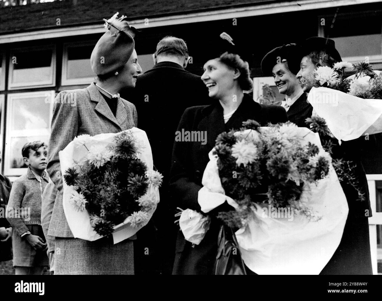 Mrs. Attlee besucht französische Widerstandskinder im Englischen Lager - Mrs. Attlee (rechts) lacht, während sie mit Madame Massigli spricht. Beide waren mit großen Sträußen überreicht worden. Frau C. R. Attlee, Frau des britischen Premierministers, M. Massigli, der französische Botschafter in London, und Madame Massigli, besuchten Wren's Warren Camp in der Nähe von Hartfield, Sussex, um sich dort für einen Monat zu treffen, bevor sie zwei Monate in ausgewählten englischen Häusern verbrachten. Oktober 1946. Stockfoto