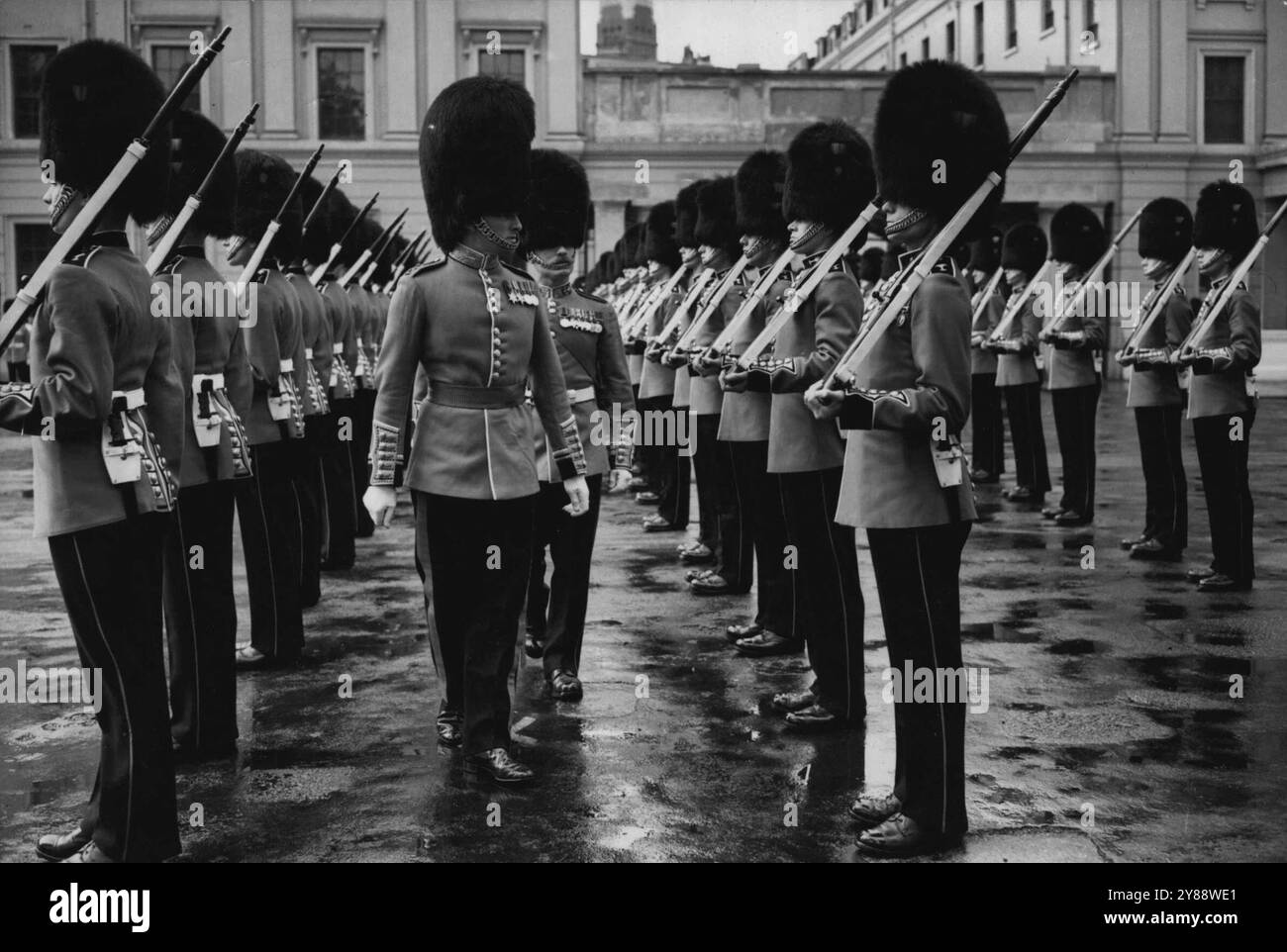 Rain stoppt die Trooping-Probe -- die walisischen Wachen, in all ihrer Pracht gekleidet, werden in Wellington Barracks inspiziert, bevor man erfuhr, dass die Trooping-the-Colour-Probe für einen Tag verschoben wurde. Die Welsh Guards trafen ihre Acarlot-Tuniken und Bärenfelle und trafen sich heute Morgen in der Wellington Barracks (London), um an einer Probe der Trooping the Colour Parade bei der Horse Guards Parade teilzunehmen. Aufgrund des Regens wurde die Probe jedoch verschoben. Es findet morgen statt, wenn das Wetter gut ist. Juni 1949. Stockfoto