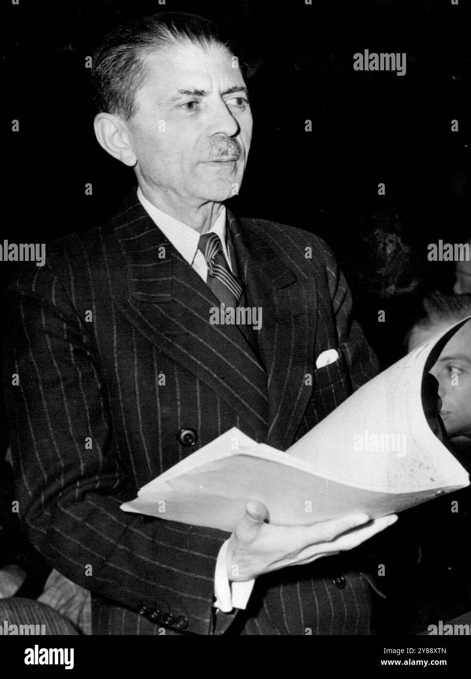 Übergibt iranische Antwort an den Sicherheitsrat New York - Hussein Ala, der den iranischen Brief an den Sicherheitsrat der Vereinten Nationen überbrachte, als er nach einer viertägigen Pause im Hunter College bei Abwesenheit des sowjetischen Delegierten wieder zusammentrat, wird mit Dokument in der Hand dargestellt, nachdem er zum Rat eingeladen wurde. Der Iran bot an, seine Anklage gegen die Sowjetunion zurückzuziehen, wenn die Russen bis zum 6. Mai den bedingungslosen Abzug aller seiner Truppen aus dem iranischen Territorium versprechen werden. März 1946. (Foto von ACME) Stockfoto