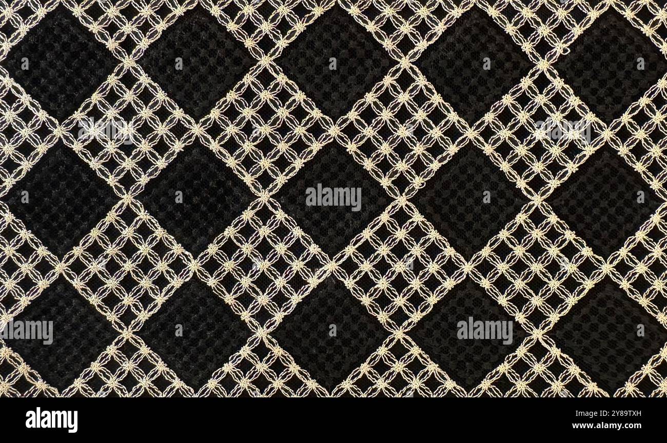 Gestrickte und gewebte Textur im Rautenmuster. Schwarzes Diamantenmuster und goldenes Blumenmuster, luxuriöse moderne klassische Mode. Naht Stockfoto