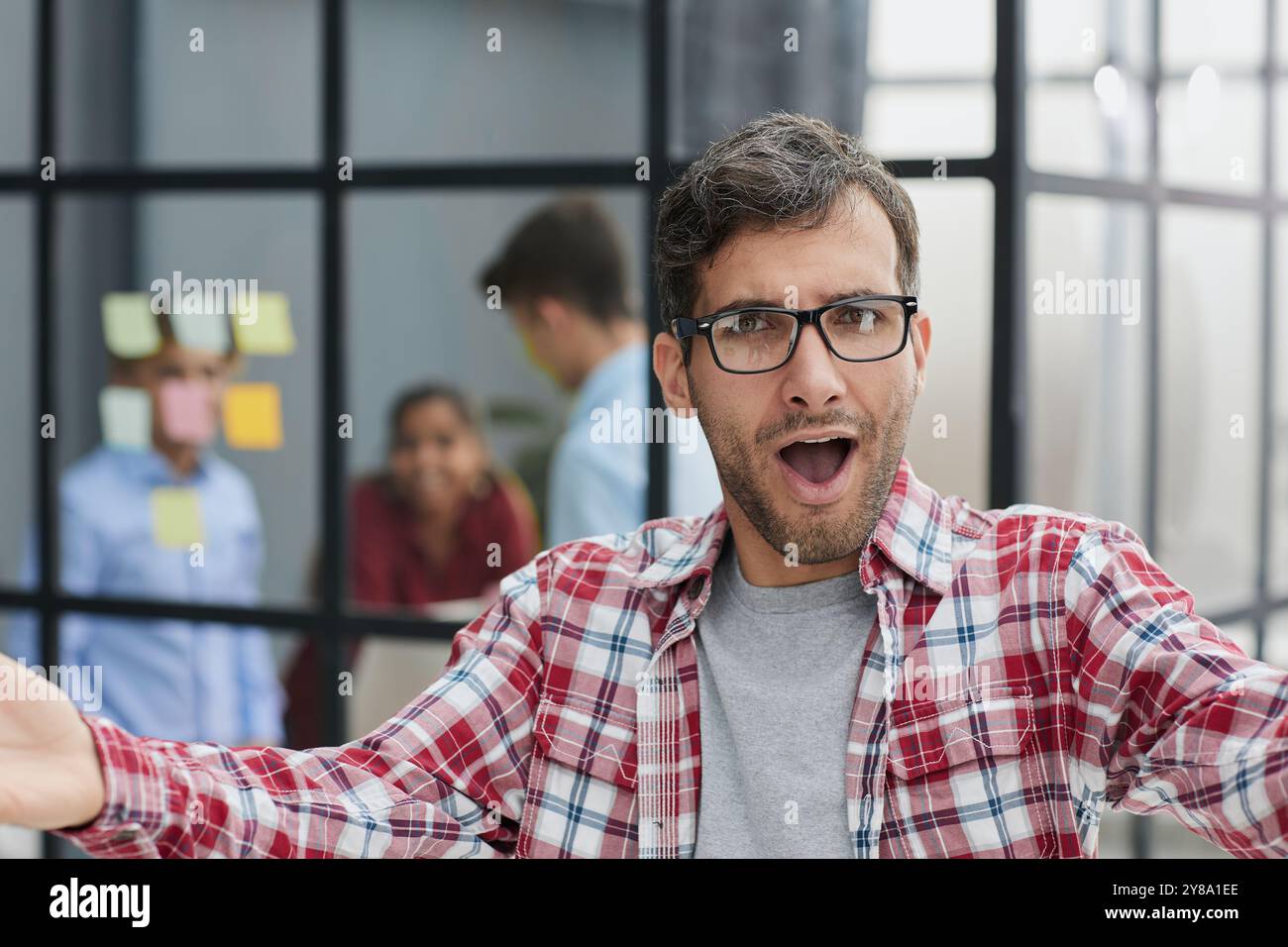 Ein gutaussehender Geschäftsmann in einem karierten Hemd spreizte seine Arme weit Stockfoto