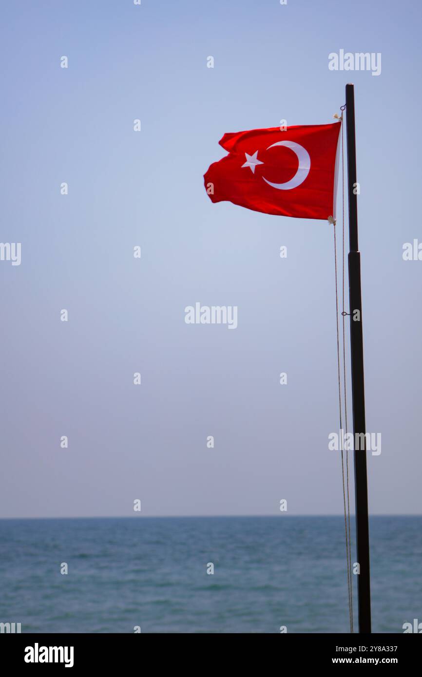 Mersin, Turkiye. 30. Juni 2023. Die türkische Nationalflagge flattert im Wind in der türkischen Stadt Mersin. Die türkische Nationalflagge besteht aus einem mittleren weißen Stern und einem Halbmond auf rotem Hintergrund. Die türkische Flagge wurde von der neuesten Version der Flagge des Osmanischen Reiches abgeleitet Stockfoto