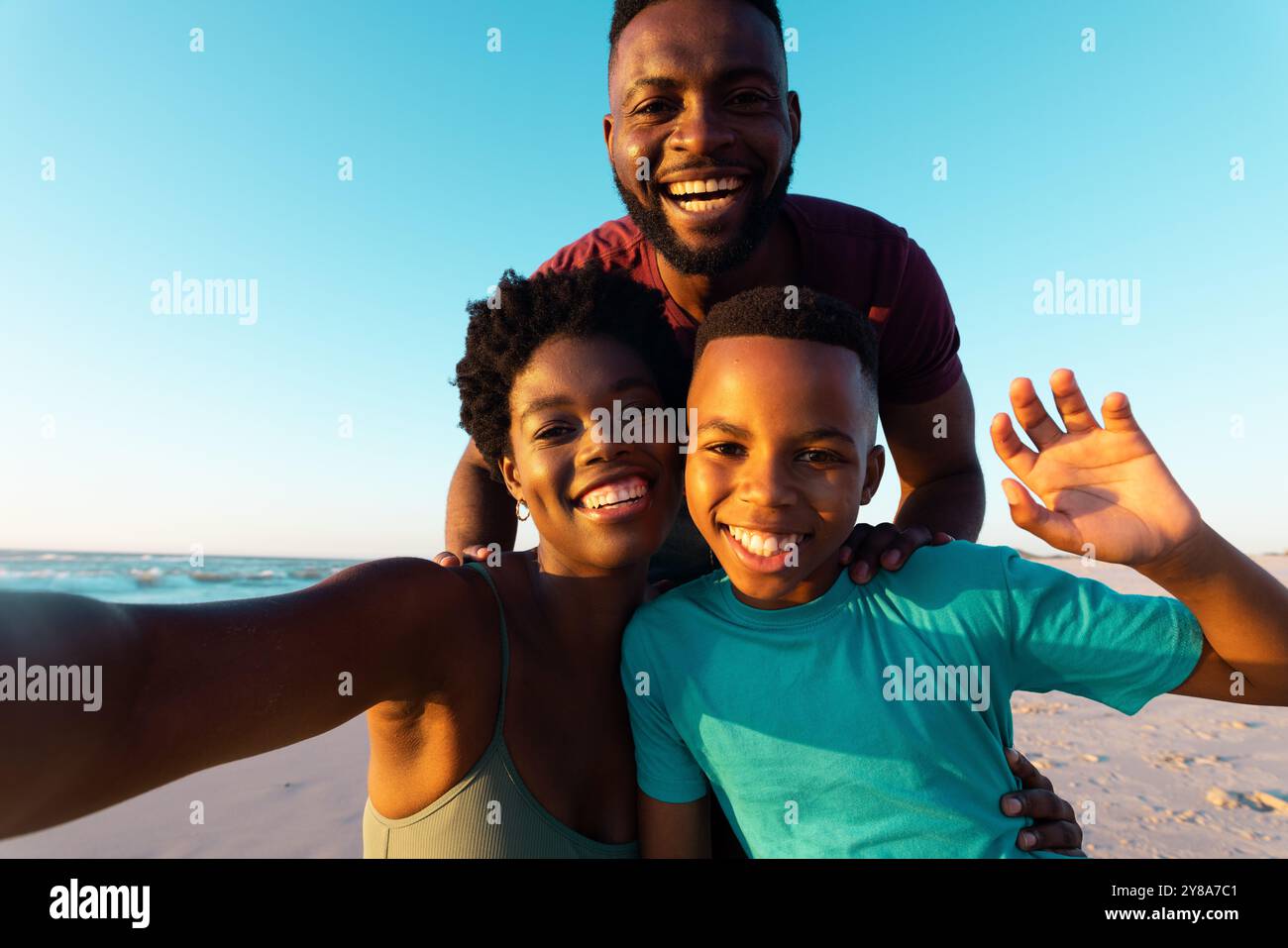 Porträt einer afroamerikanischen Frau, die Selfie mit glücklichem Mann und Sohn am Strand vor dem Himmel macht Stockfoto