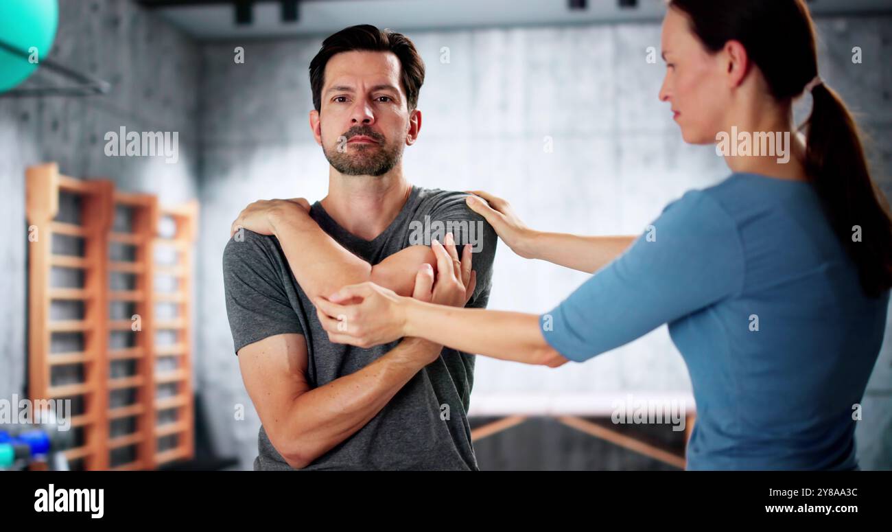 Eine Physiotherapeutin gibt Eine männliche Schulterübung in der Klinik Stockfoto