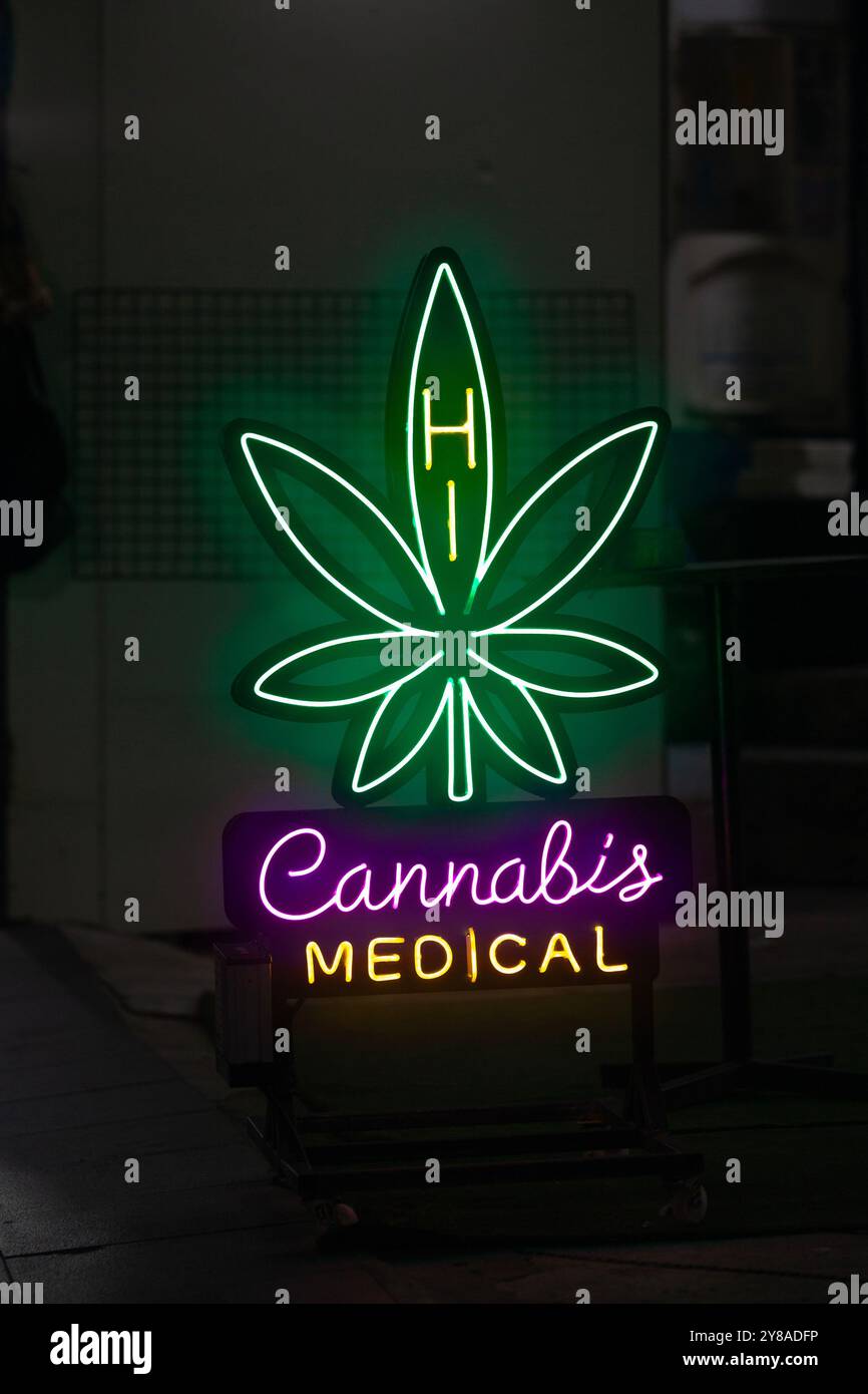 Ein Neonlicht vor einem Laden, geformt in ein Cannabisblatt mit der Botschaft: Hi, Cannabis Medical. Stockfoto