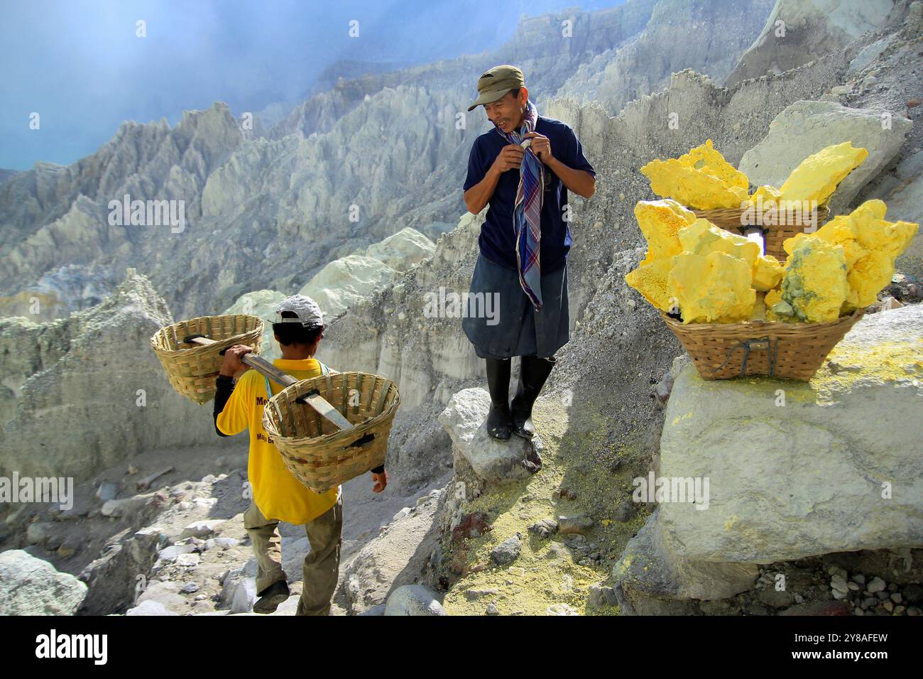 Schwefelbergleute machen eine kurze Pause, wenn sie Schwefel mit einer durchschnittlichen Belastung von 70-90 kg im Ijen-Krater transportieren. Stockfoto