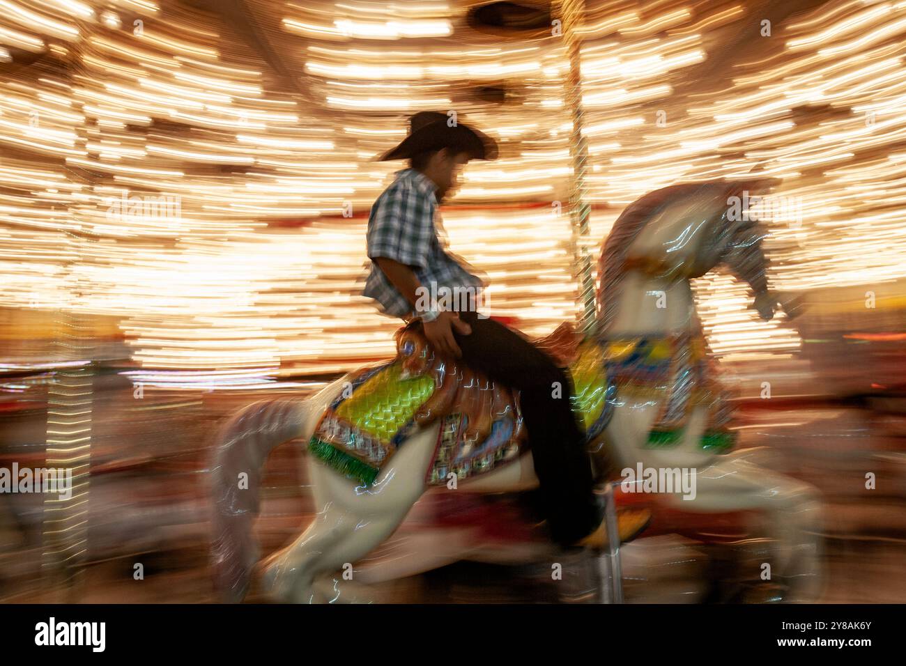 Junger Cowboy, der auf Karussell reitet, Bewegungsunschärfe Stockfoto