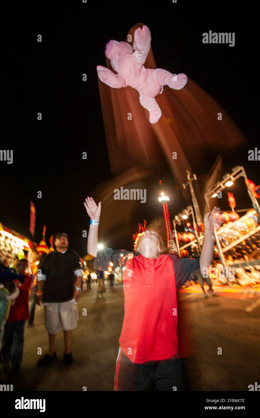 Junge wirft Plüschschwein in die Luft und fängt es ein Stockfoto