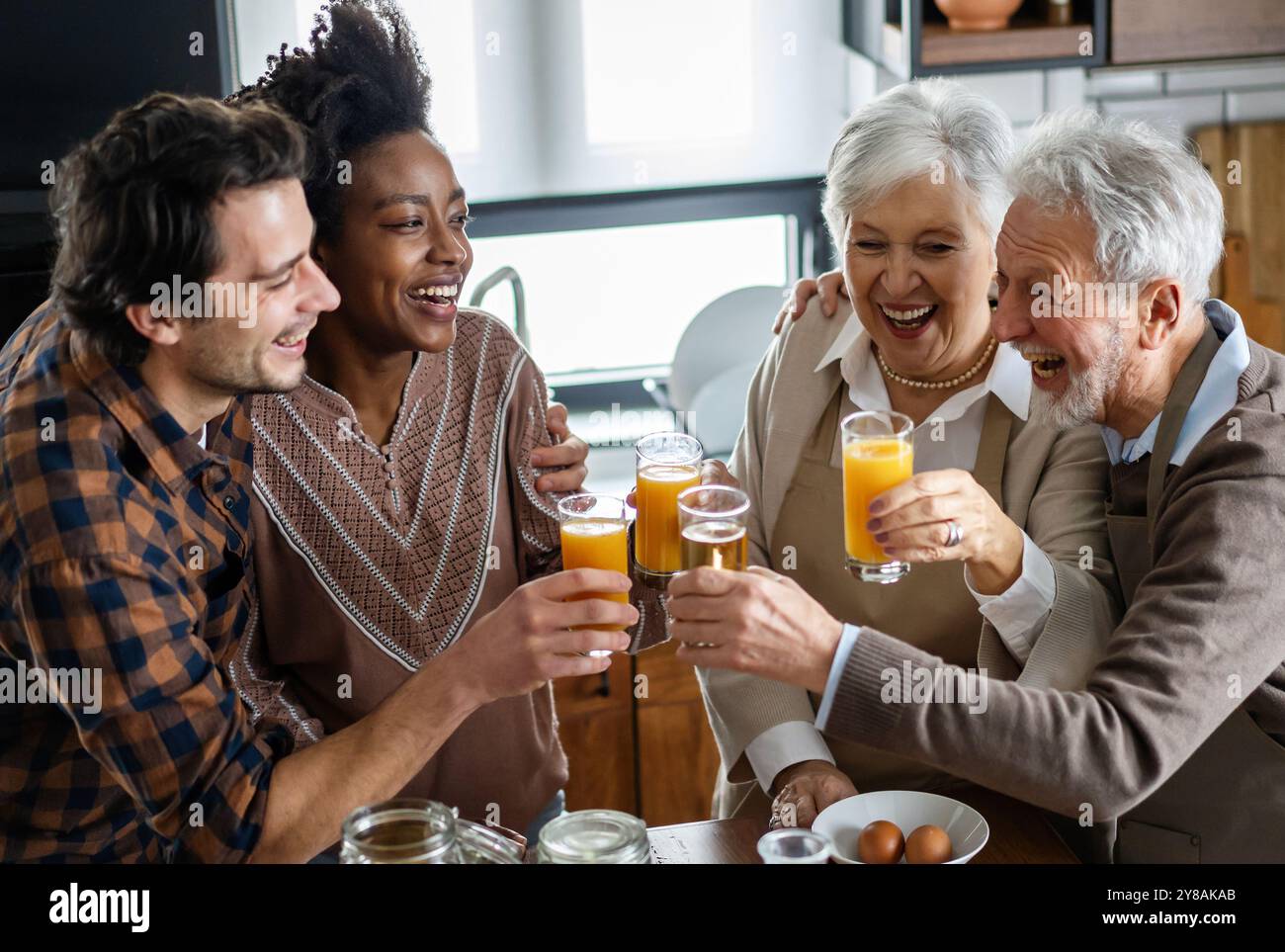 Mehrere Generationen multiethnische Familie, die Spaß hat, um sich an einem festlichen Küchentisch zu unterhalten. Stockfoto