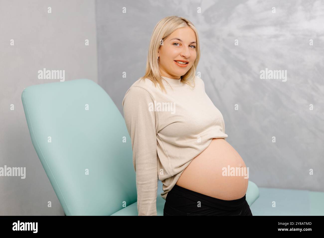 Junge Schwangere, die während einer ärztlichen Beratung mit dem Gynäkologen auf dem gynäkologischen Stuhl sitzt Stockfoto