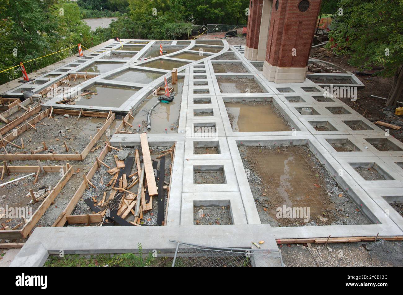 Im Bau unvollendetes Bauprojekt mit Beton und Holz. Orangefarbene Kegel und Schlauch auf dem Boden. Architektur Betongestaltungsplatz Stockfoto