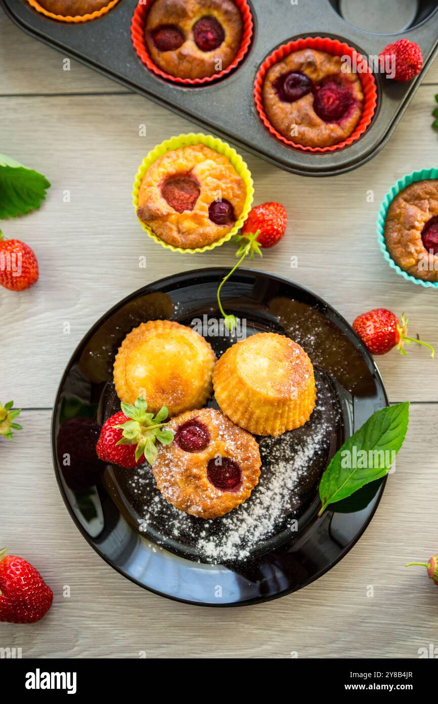 Süße Quark-Muffins mit Erdbeerfüllung, auf einem Teller auf einem Holztisch. Stockfoto