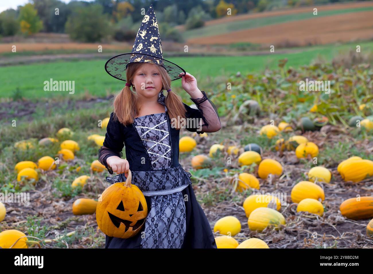 Kleines Mädchen in Hexenkostüm spielt im Herbstpark. Kind hat Spaß an Halloween Trick or Treat. Kinder tricksen oder behandeln. Kleinkind mit Jack-o-lan Stockfoto