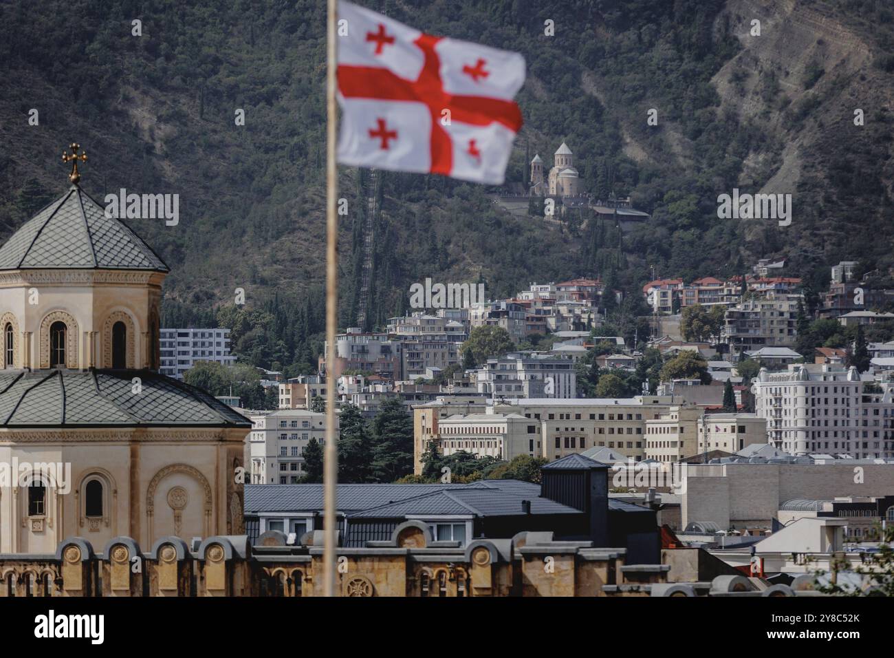 Die Flagge Georgiens fliegt über der Stadt in Tiflis, 14. September 2024. Am 26. Oktober 2024 wird das parlament in Georgien gewählt. Die Wahlen werden als wichtiger Wegweiser für das Land hinsichtlich seiner Ausrichtung auf Russland oder auf die Europäische Union angesehen. Gewalttätige Proteste gegen die derzeitige Regierungspartei Georgian Dream sorgten im Frühjahr 2023 und Frühjahr 2024 für internationalen Aufruhr, nachdem das umstrittene "Agent Law" umgesetzt wurde, das Parallelen zum 2012 in Russland verabschiedeten Gesetz hat und die Aktivitäten ausländischer Nichtregierungsorganisationen stark einschränkt. Stockfoto