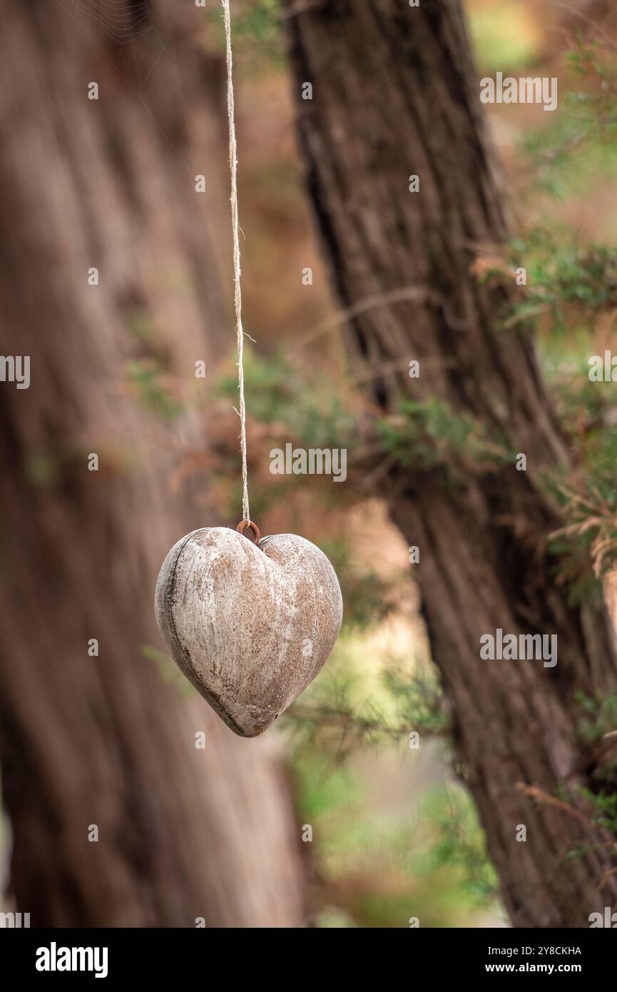 Hölzerne Herzdekoration hängt an einem einzelnen Strang oder einer Schnur von einem Baum in einer griechischen Taverne als dekoratives Objekt. Stockfoto