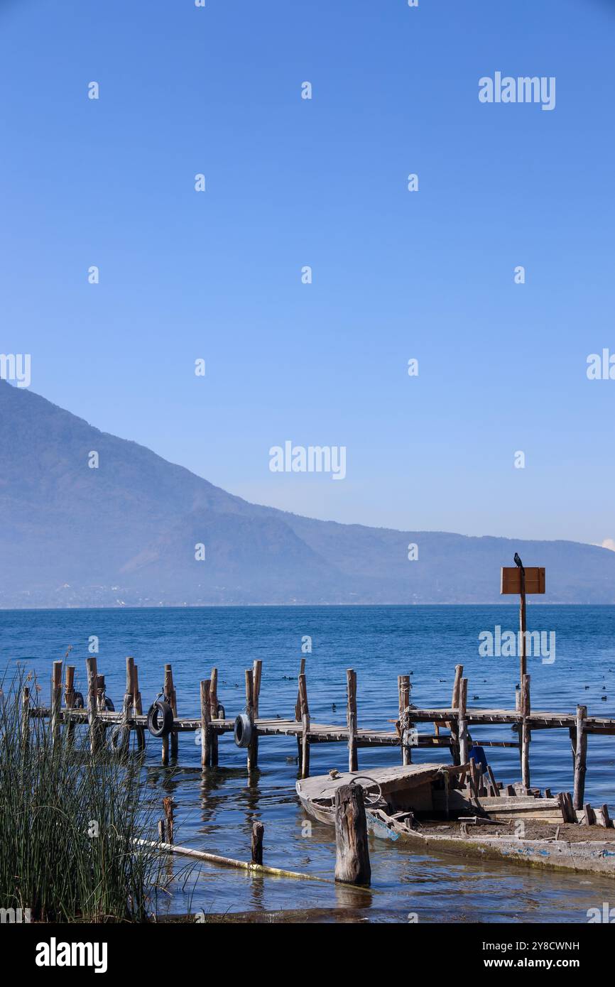 Ein halb untergetauchtes Schiff auf dem Atitlan-See. Rustikaler, alter Steg im Dorf Palopo. Ruhiger See im guatemaltekischen Hochland, Zentralamerika. Stockfoto