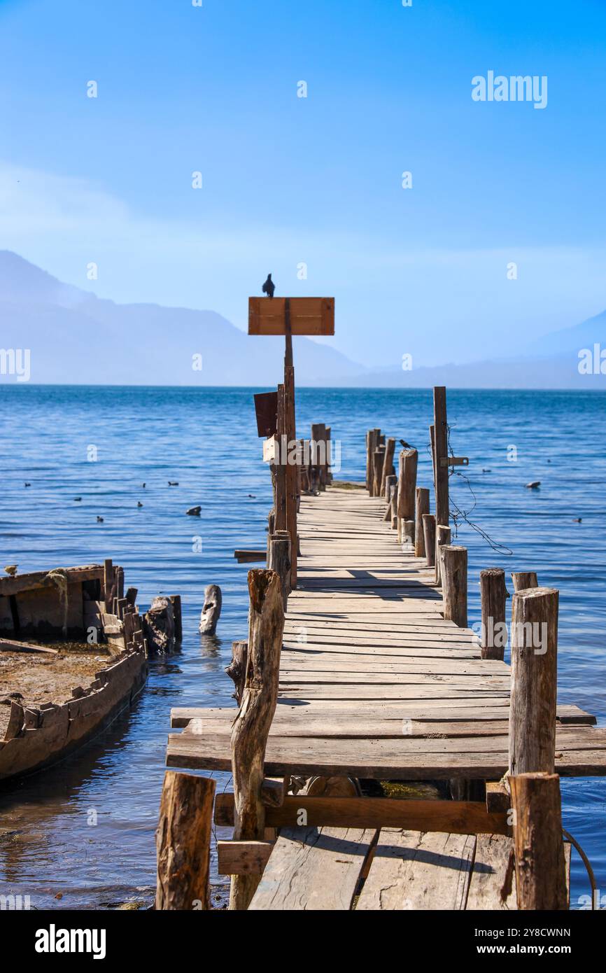 Ein halb untergetauchtes Schiff auf dem Atitlan-See. Rustikaler, alter Steg im Dorf Palopo. Ruhiger See im guatemaltekischen Hochland, Zentralamerika. Stockfoto
