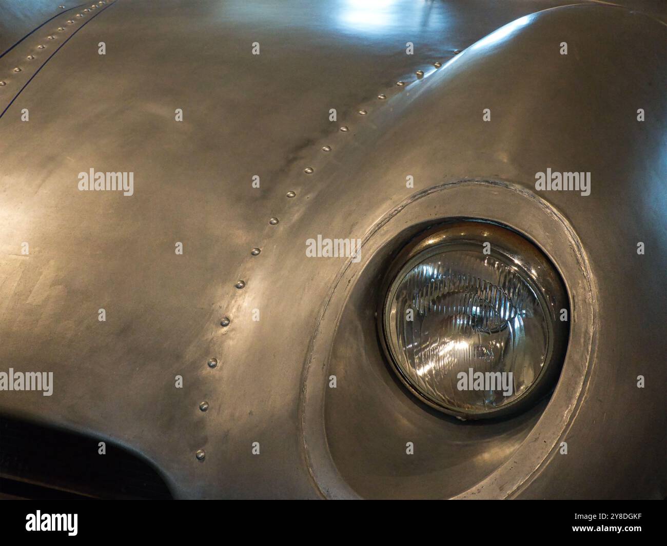 Detail des Scheinwerfers eines Oldtimer-Sportwagens mit Aluminiumkarosserie. Stockfoto
